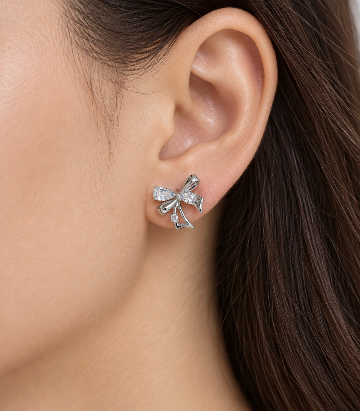 JIMIKI Asymmetric Crystal Bow Stud Earring Pair in Silver / Clear, close-up detail #color_silver / clear