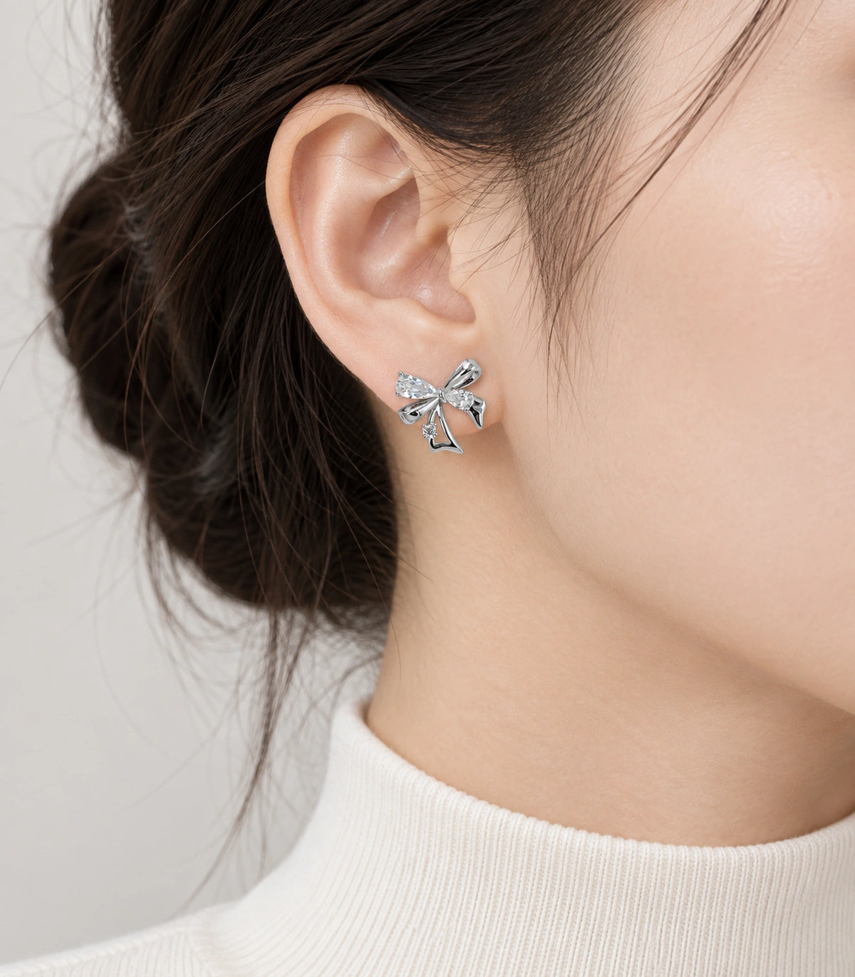 JIMIKI Asymmetric Crystal Bow Stud Earring Pair in Silver / Clear, model wearing view #color_silver / clear