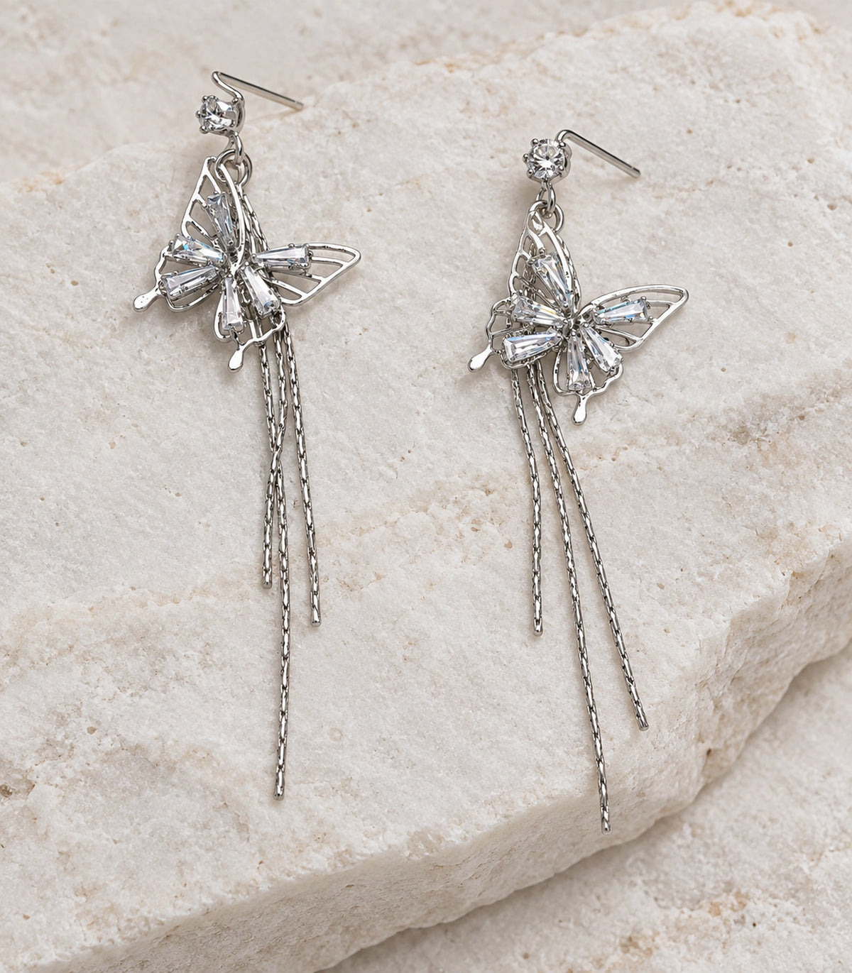 JIMIKI Silver Tone Baguette Butterfly Three Chain Earring Pair in Silver-tone, editorial flat lay