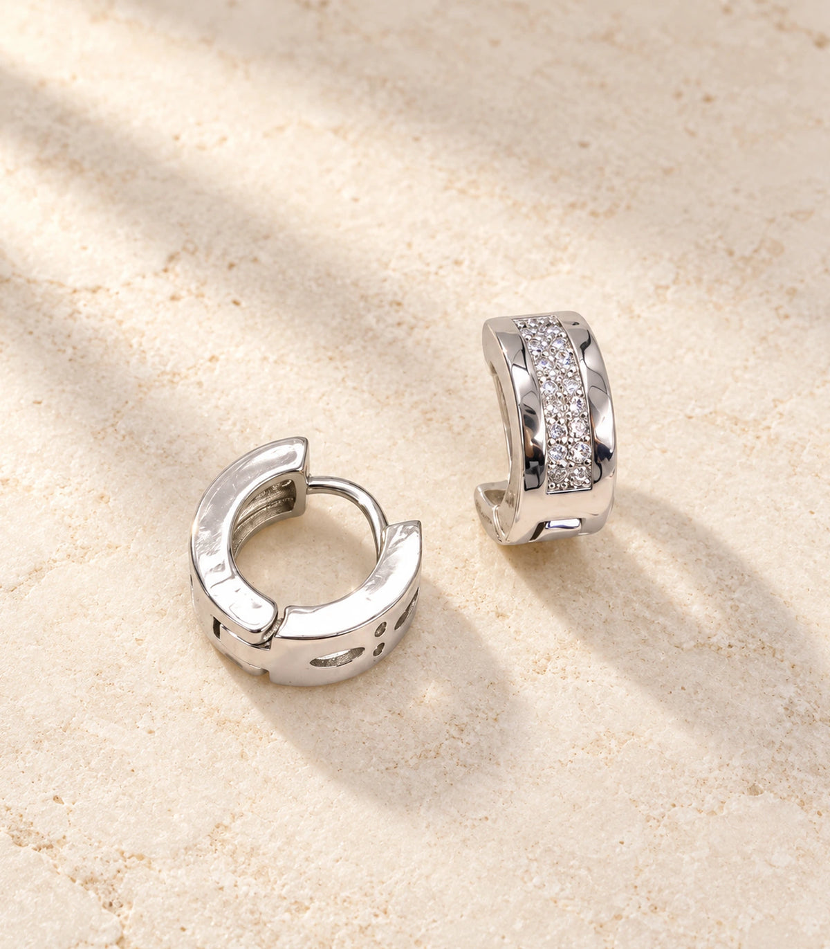 JIMIKI Silver central pave strip huggie hoop earrings, pair on pale textured stone #color_silver