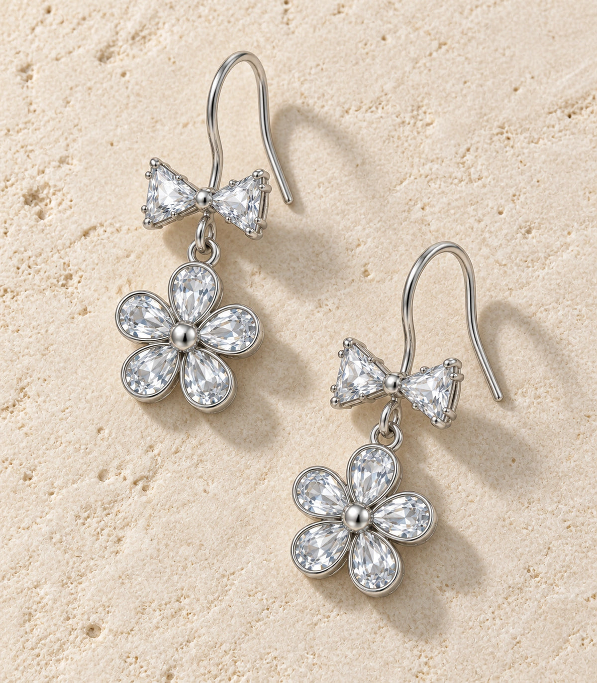 JIMIKI Silver Tone Clear Bow Five Petal Flower Drop Earring Pair in Silver tone / clear, editorial flat lay
