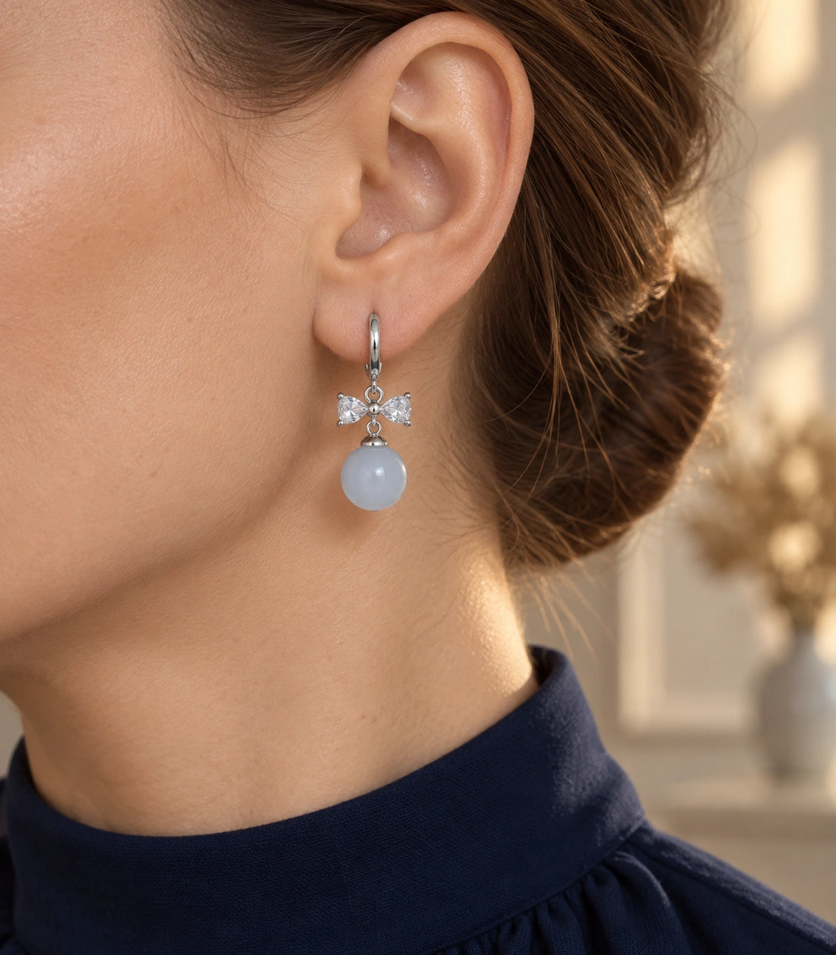 JIMIKI Silver-Tone Clear Crystal Bow Pale Blue Bead-Drop Huggie Earrings in Silver / Clear / Pale Blue, editorial model view