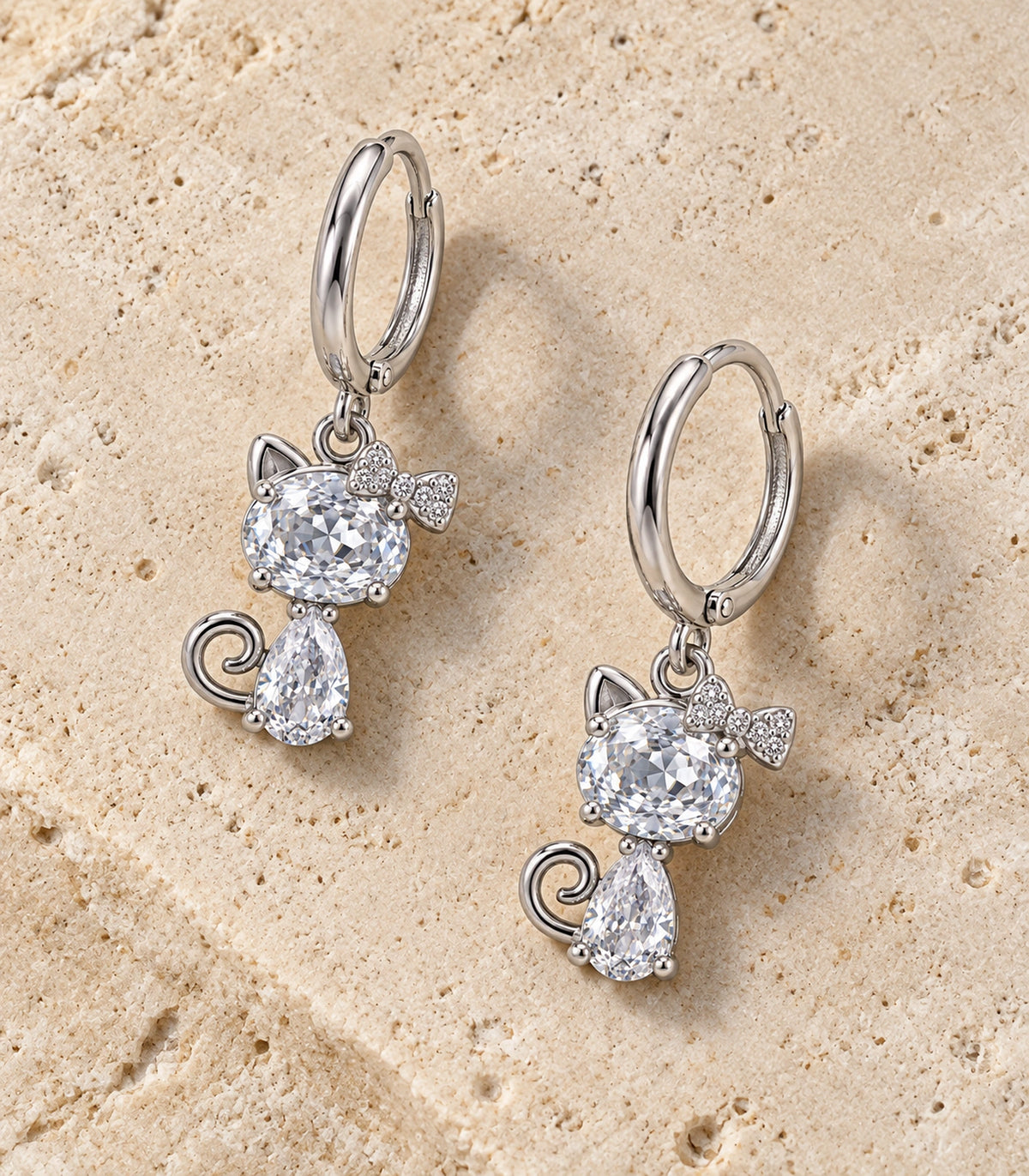 JIMIKI Silver Tone Clear Crystal Cat Bow Hoop Earring Pair in Silver tone / clear, editorial flat lay