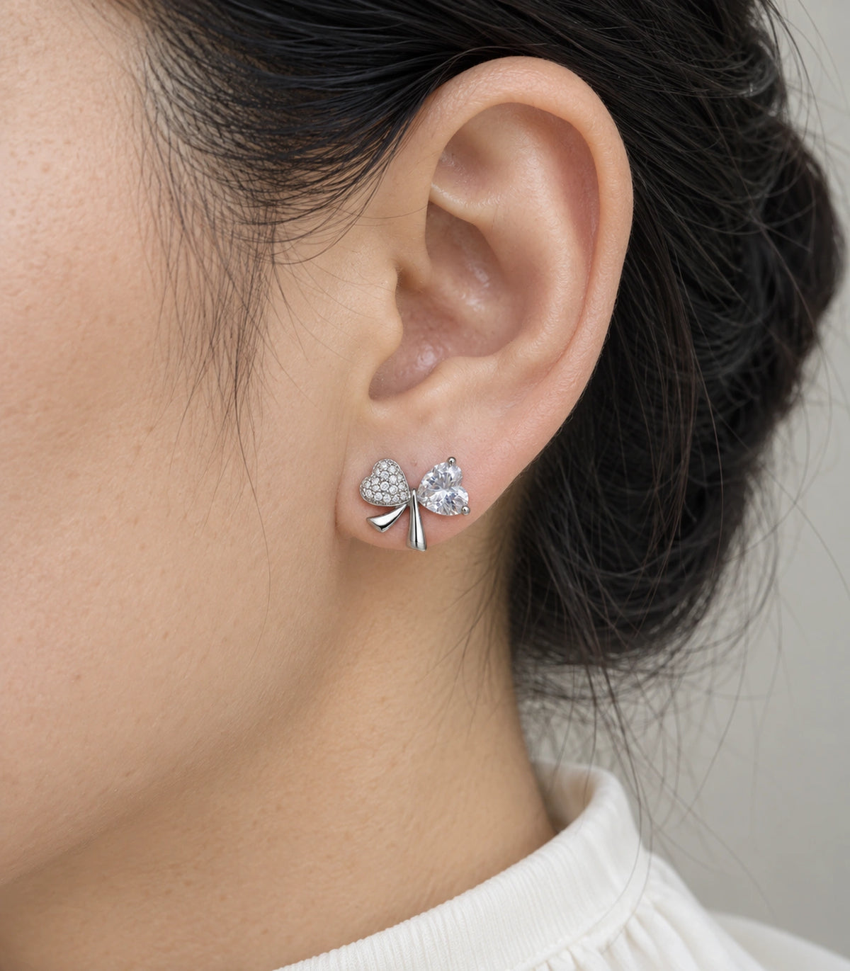 JIMIKI Silver Tone Clear Heart Bow Stud Earring Pair in Silver tone, close-up detail