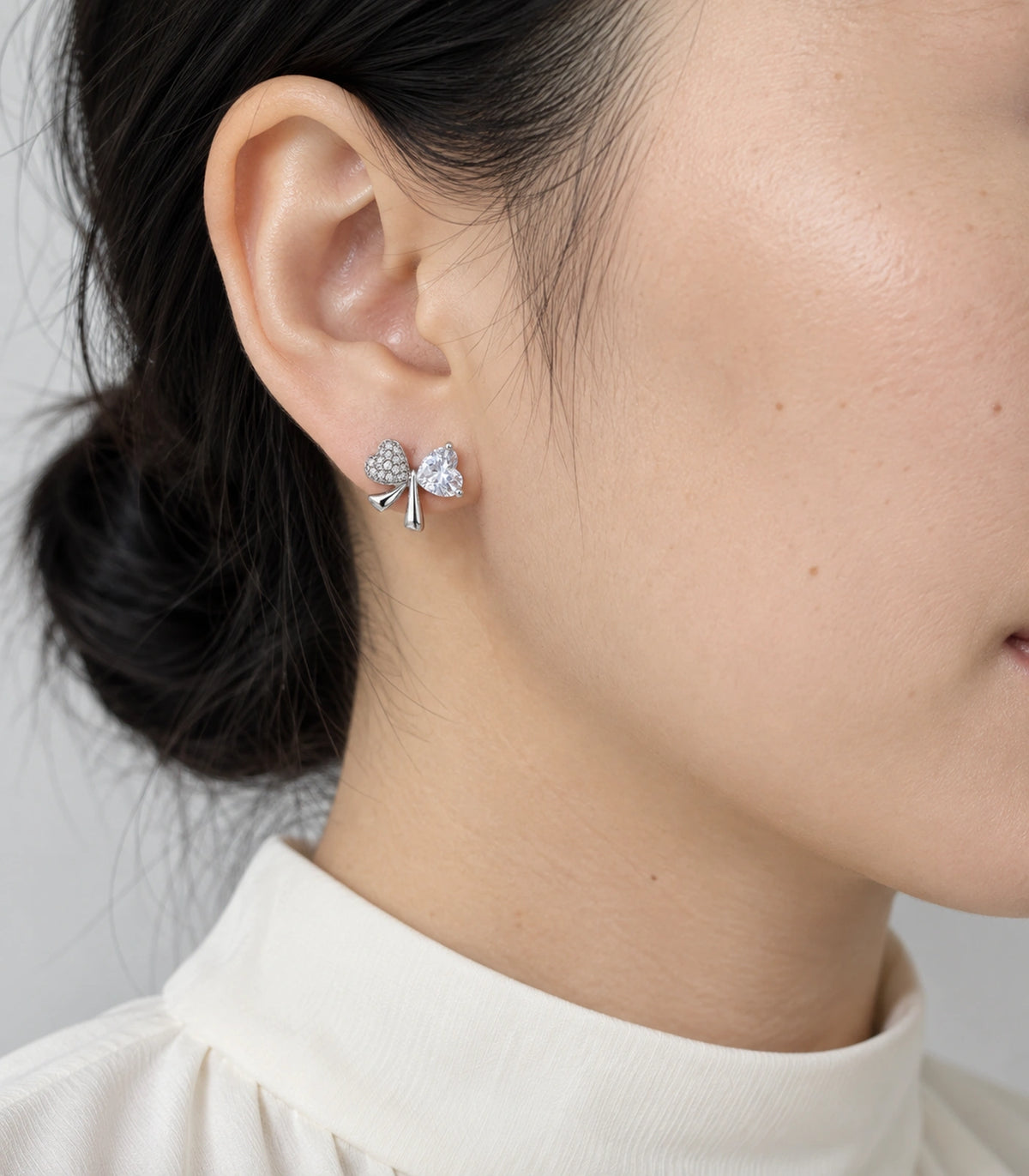 JIMIKI Silver Tone Clear Heart Bow Stud Earring Pair in Silver tone, model wearing view