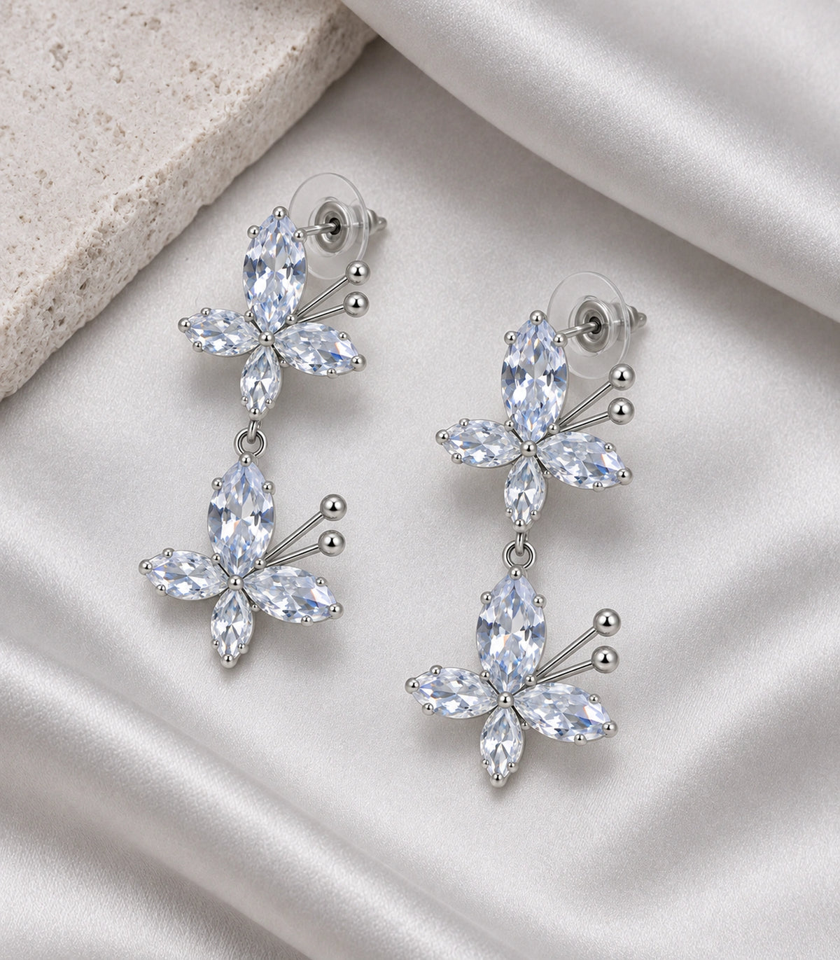 JIMIKI Silver Tone Clear Marquise Double Butterfly Drop Earring Pair in Clear / Silver, editorial flat lay