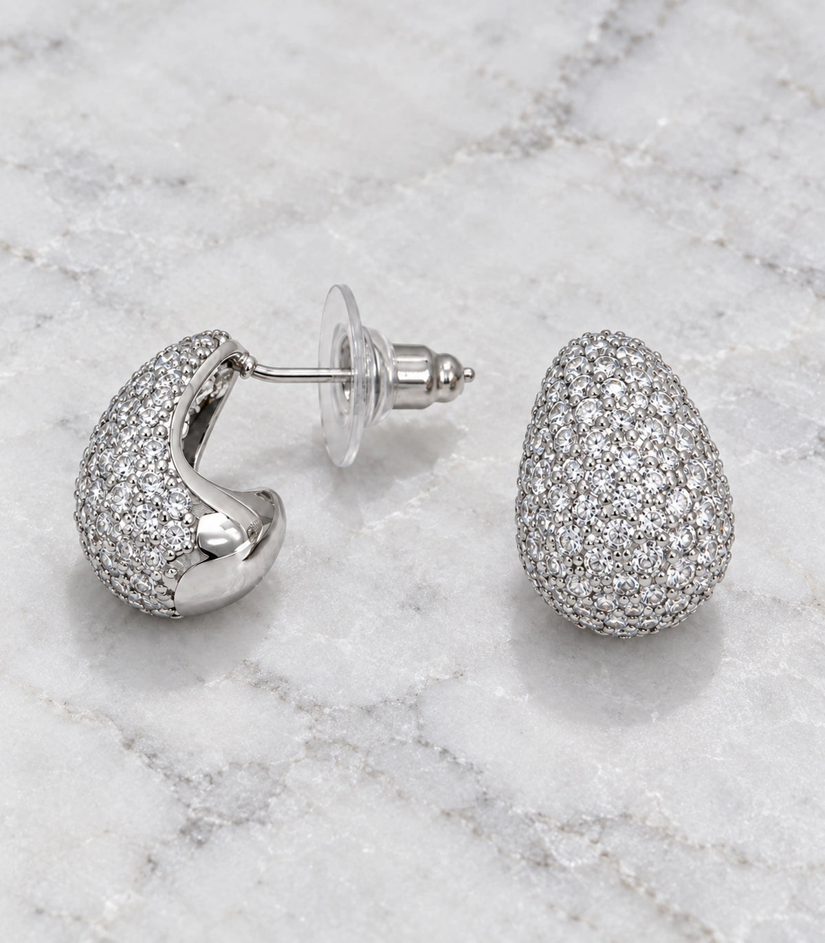 JIMIKI Silver Tone Clear Pave Domed Teardrop Stud Earring Pair in Silver tone/Clear, editorial flat lay