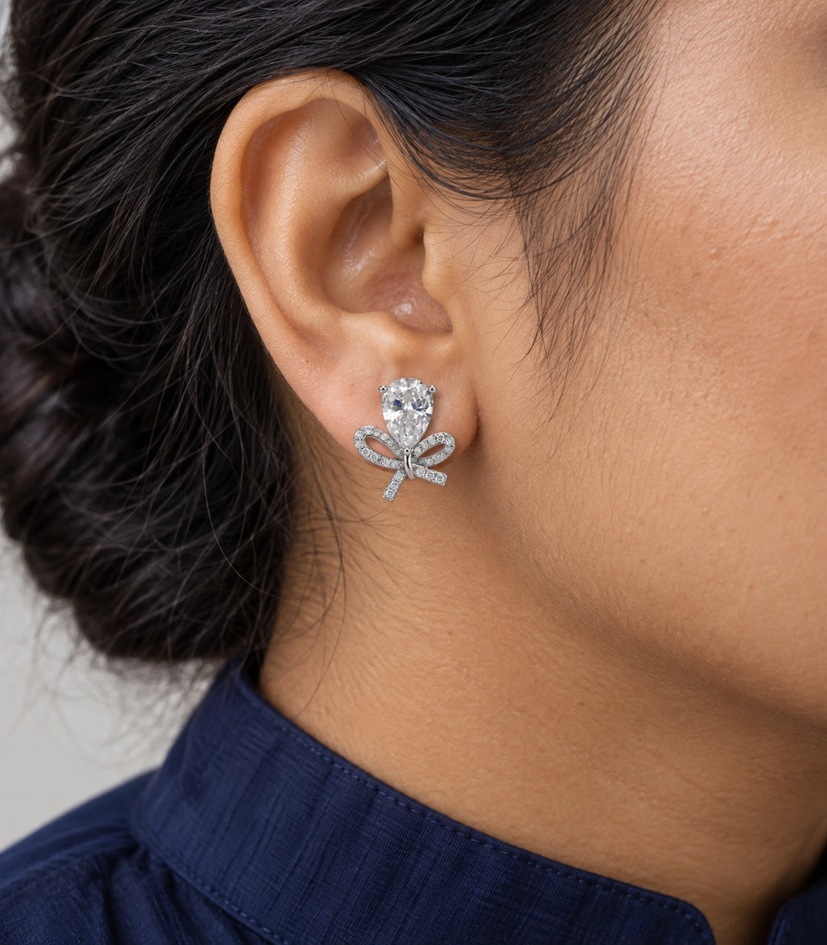 JIMIKI Silver Tone Clear Pear Crystal Bow Stud Earring Pair in Silver-tone, close-up detail