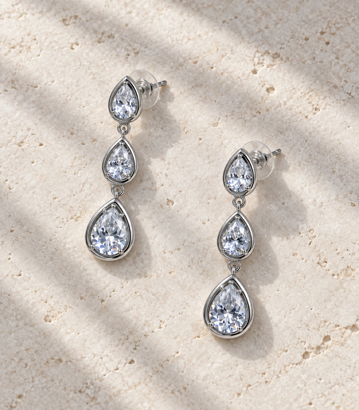 JIMIKI Silver Tone Clear Triple Teardrop Drop Earring Pair in Silver Tone, editorial flat lay