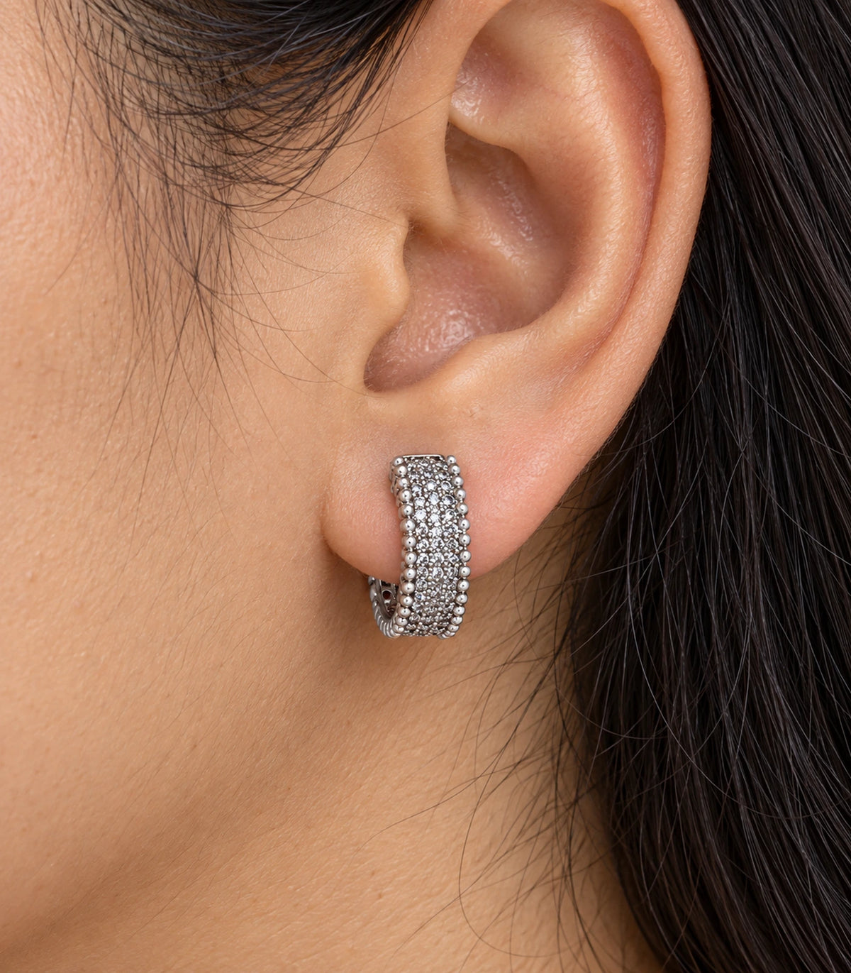 JIMIKI Silver Crystal Bead Border Huggie Hoop Earrings, shown worn on the ear #color_silver