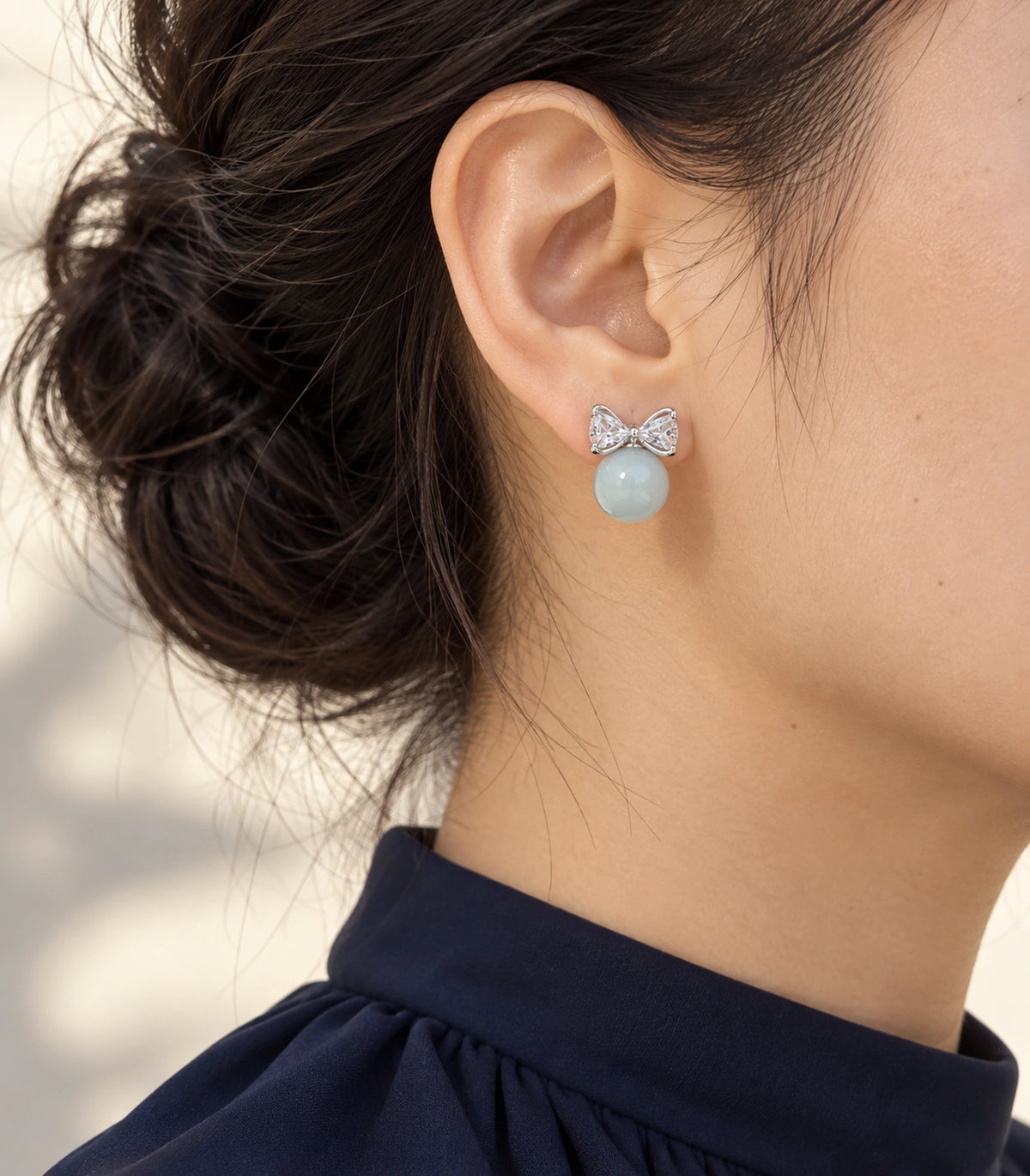 JIMIKI Silver-Tone Crystal Bow Blue Bead Stud Earrings in Silver-tone / pale blue, editorial model view