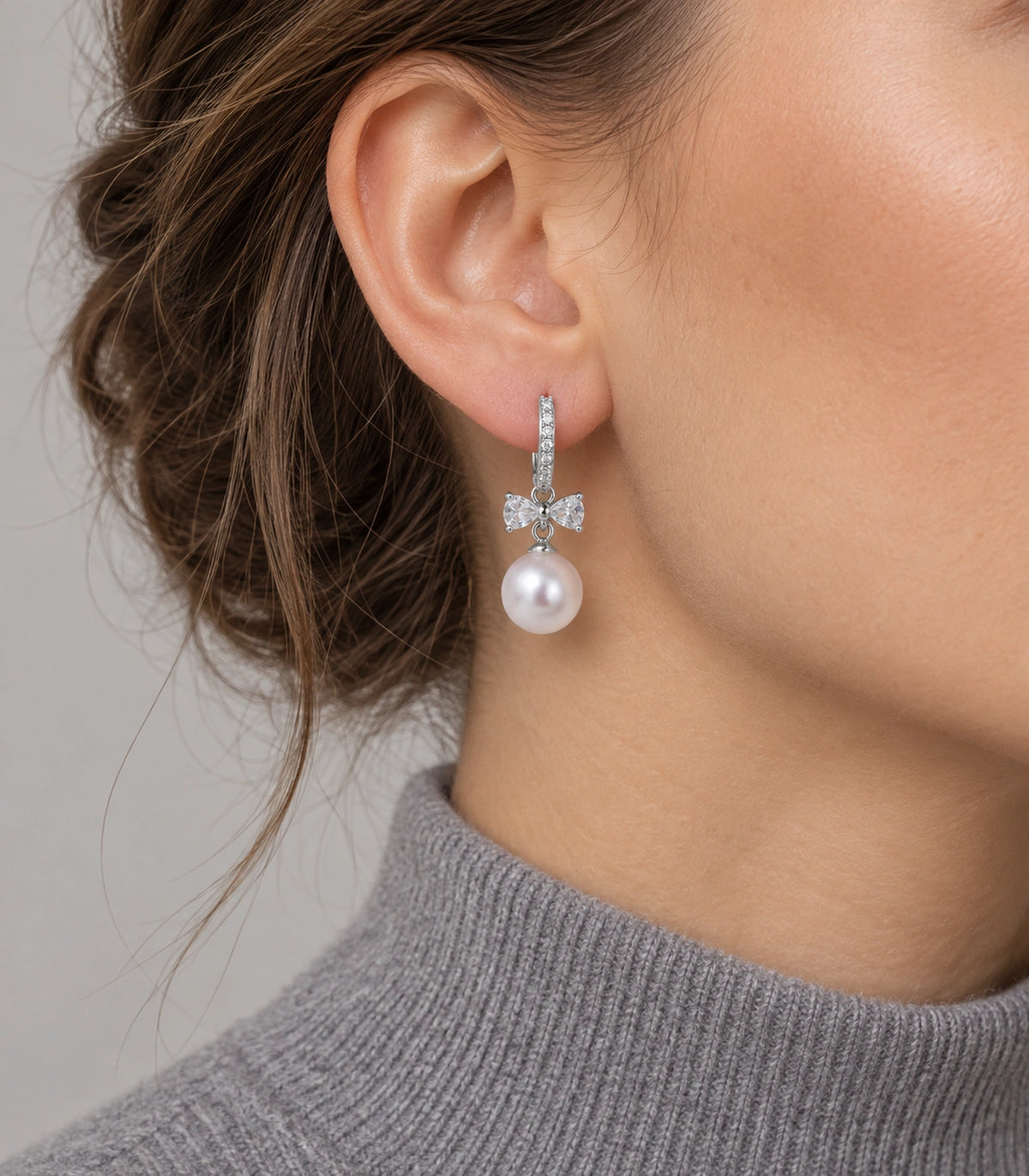 JIMIKI Silver-Tone Crystal Bow Pearl-Drop Huggie Earrings in Silver / Clear / White, model wearing view