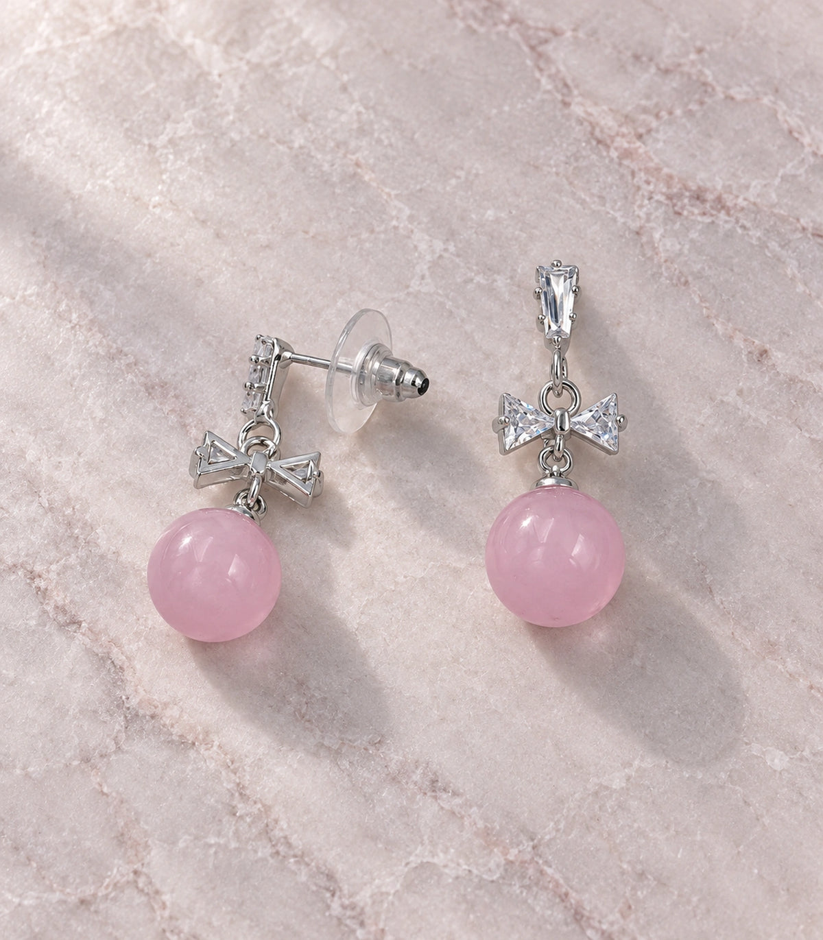 JIMIKI Silver-Tone Crystal Bow Pink Bead Drop Earrings in Silver / Clear / Pink, editorial flat lay