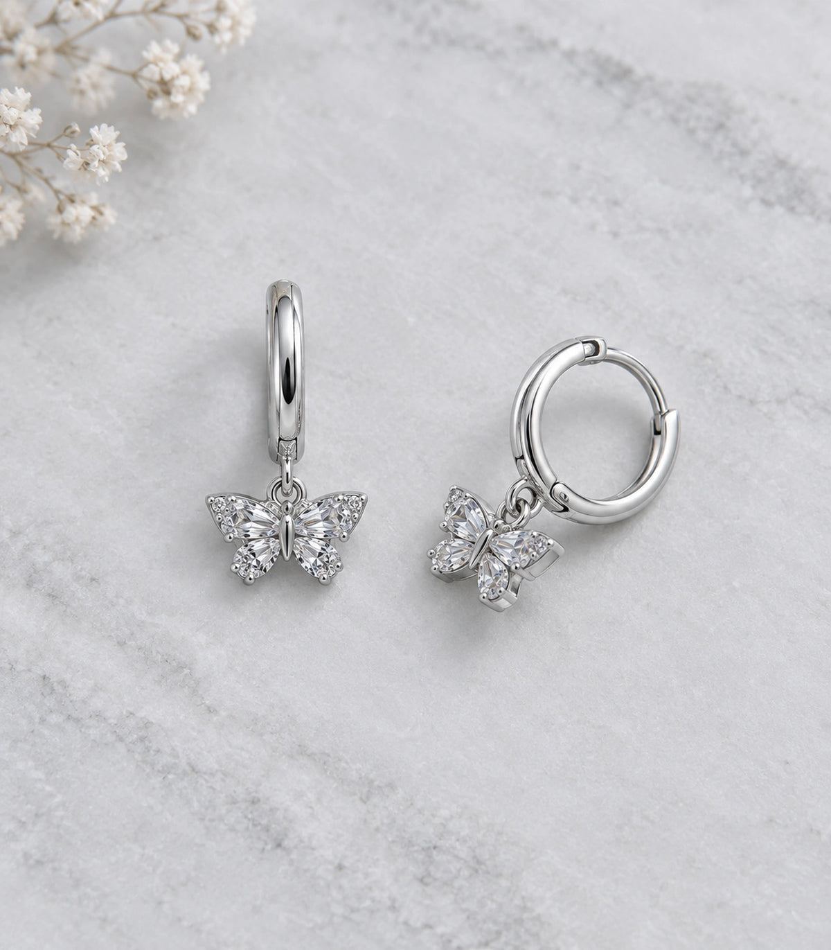JIMIKI Crystal Butterfly Huggie Earrings in Silver / Clear, editorial flat lay #color_silver / clear
