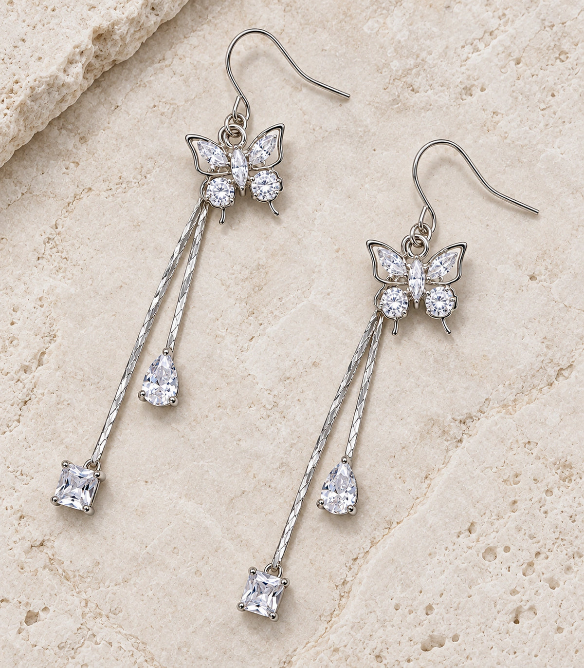 JIMIKI Silver Tone Crystal Butterfly Teardrop Tassel Earring Pair in Silver tone, editorial flat lay