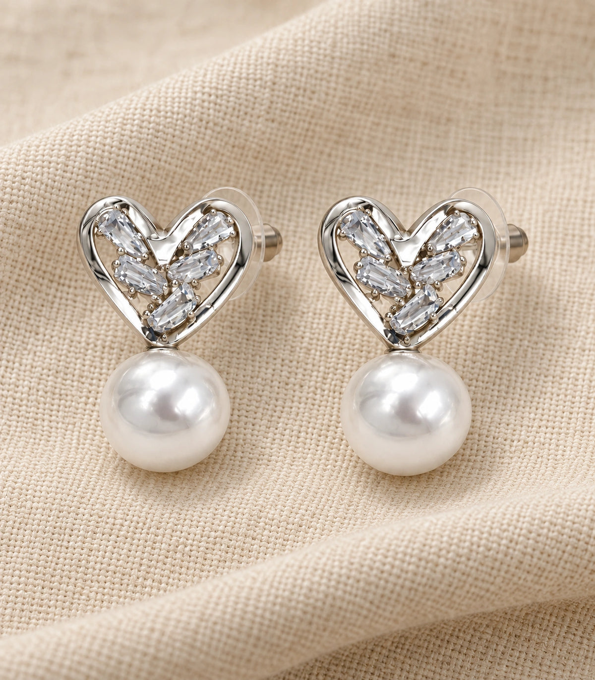 JIMIKI Silver-Tone Crystal Heart Pearl Drop Stud Earrings in Silver Tone, editorial flat lay