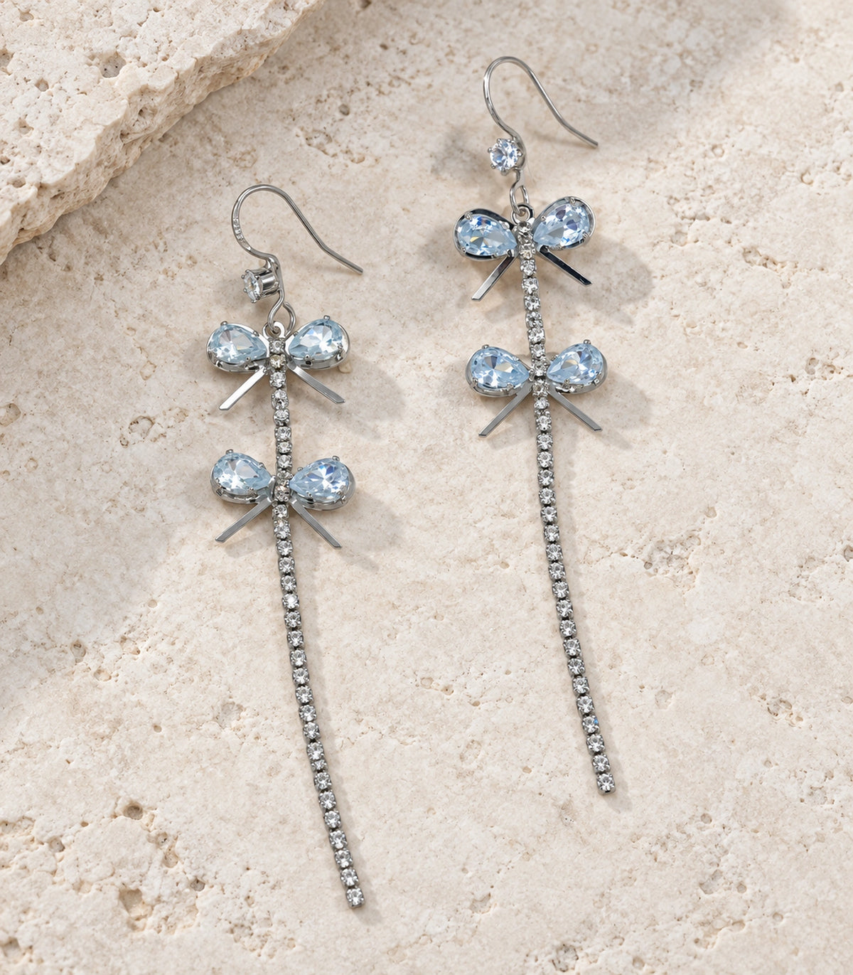 JIMIKI Silver Tone Double Crystal Bow Tassel Earring Pair in Silver-tone, editorial flat lay