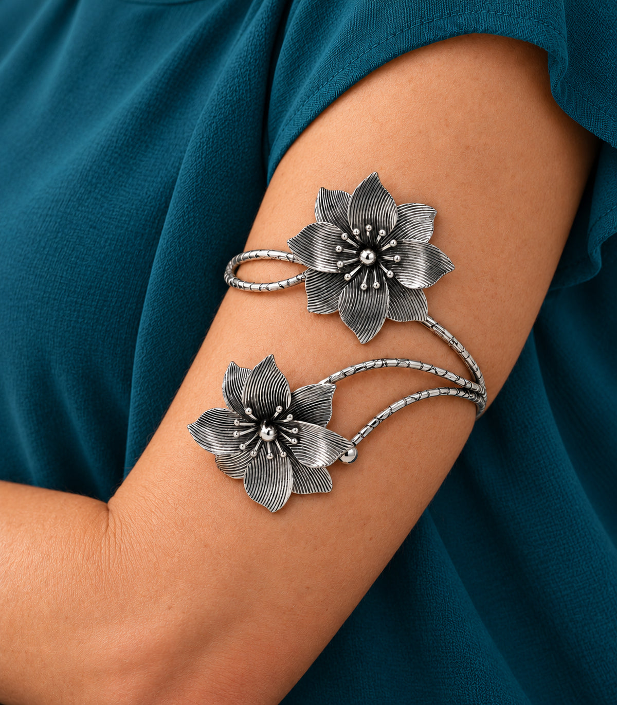 Close view of the silver-tone cuff's layered ribbed flowers and bead-tipped stamens on the upper arm