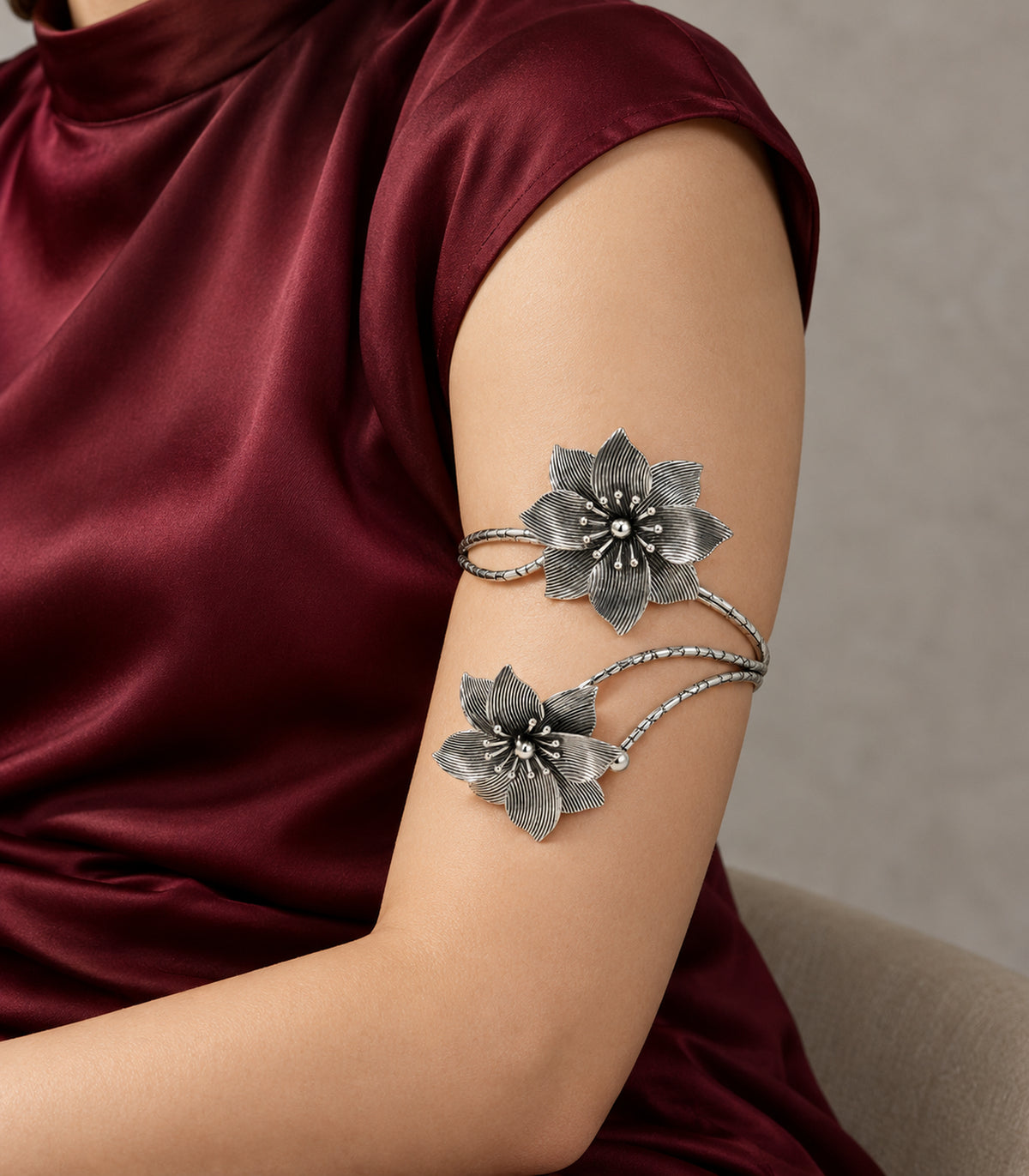 Silver-tone double-flower arm cuff on the upper arm with a burgundy outfit