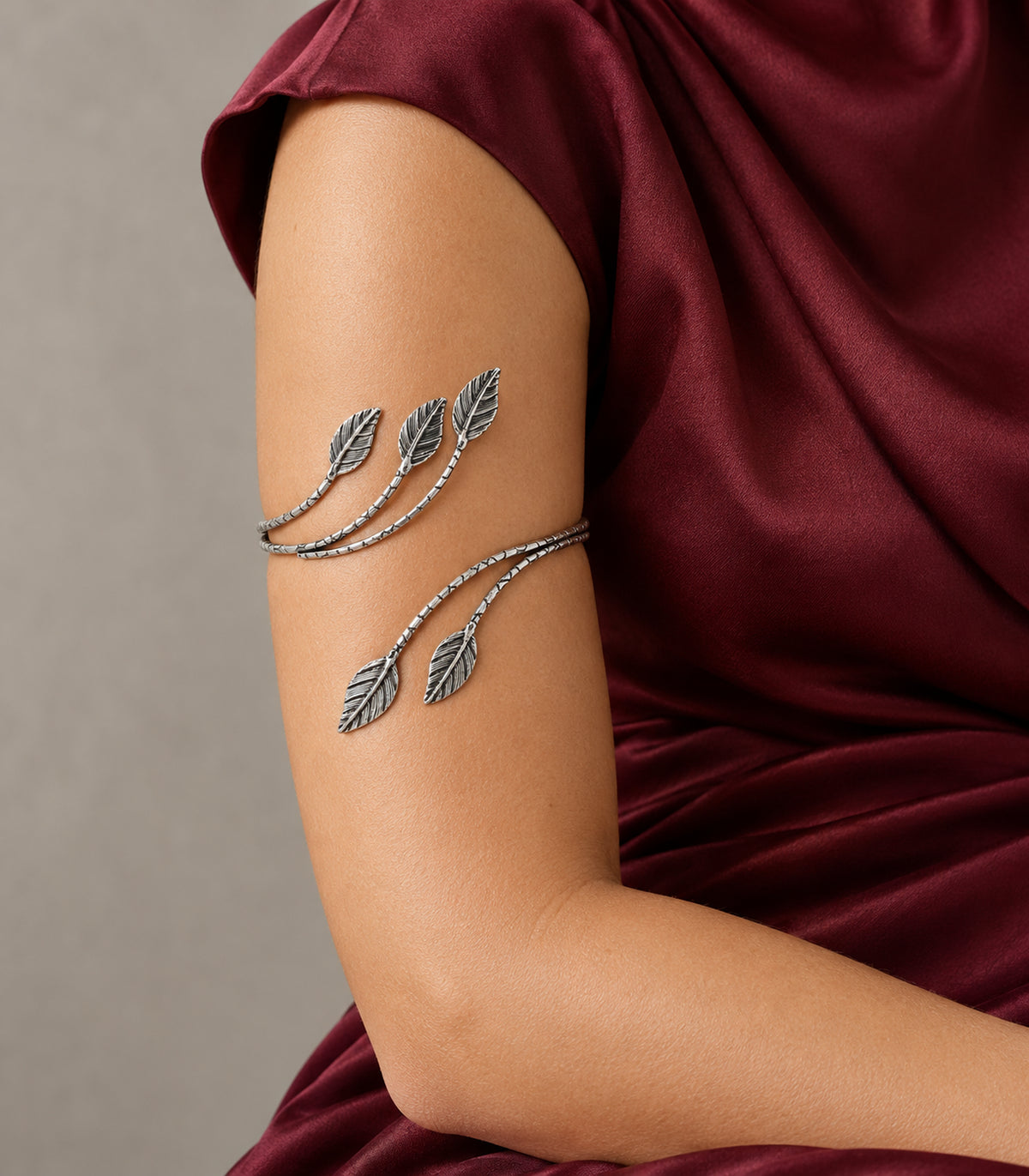 Silver-tone five-leaf branch cuff worn on upper arm with burgundy clothing