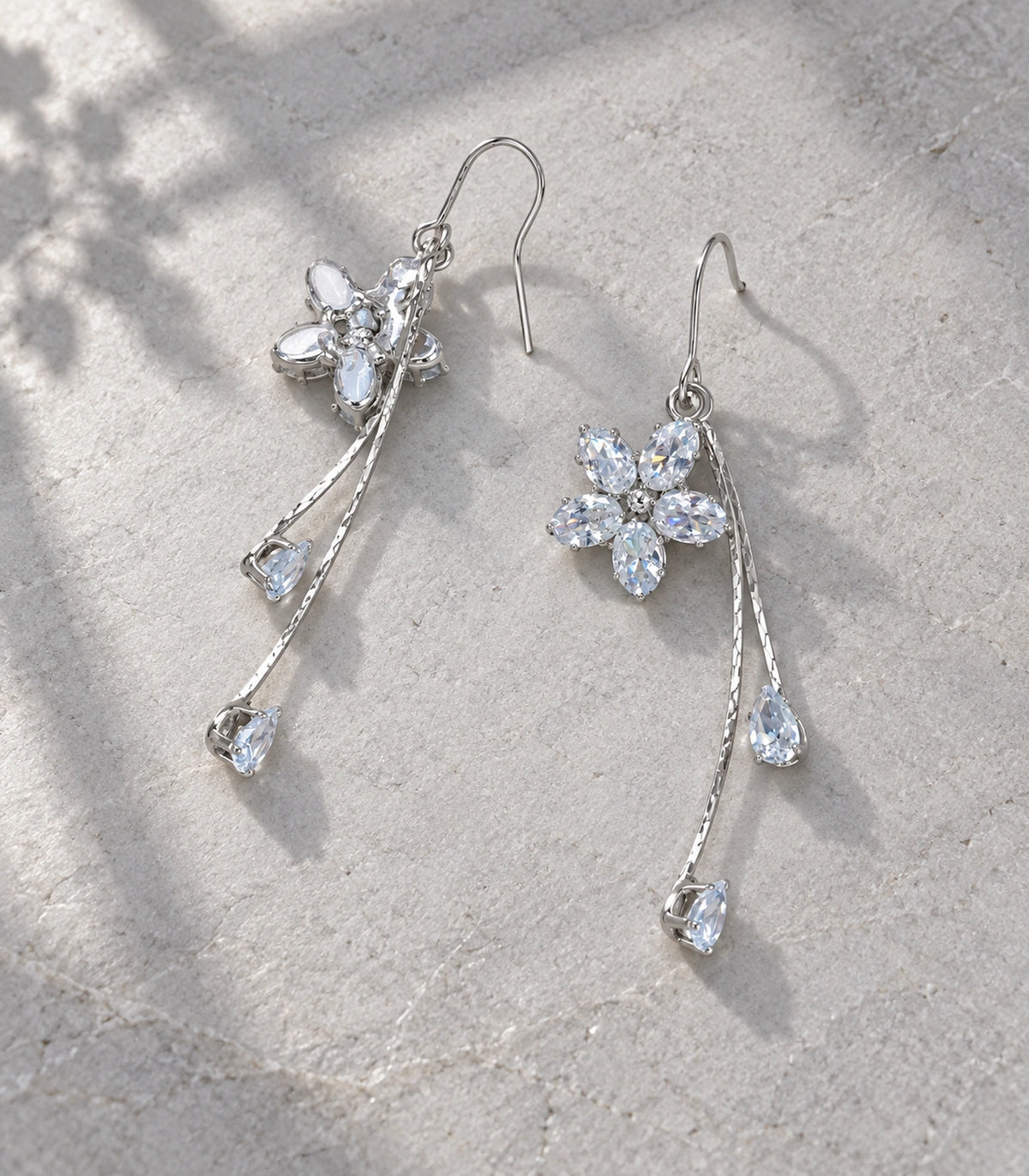 JIMIKI Silver-Tone Five-Petal Crystal Flower Twin Pear Drop Earrings in Silver Tone, editorial flat lay