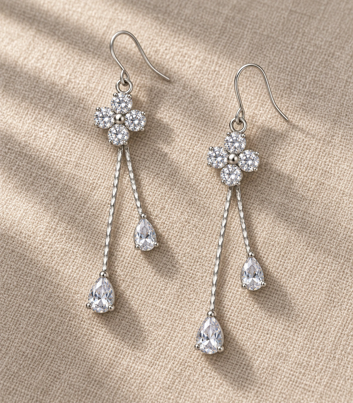 JIMIKI Silver-Tone Four Round Crystal Flower Twin Pear Drop Earrings in Silver Tone, editorial flat lay