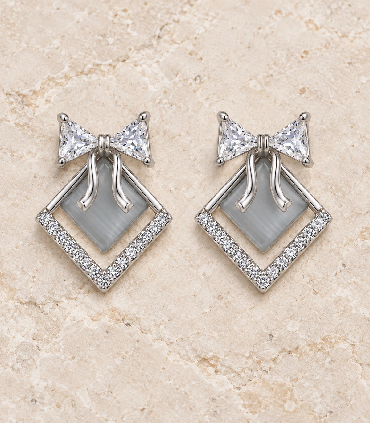 JIMIKI Silver Tone Grey Diamond-Shaped Bow Crystal Stud Earring Pair in Silver tone, editorial flat lay