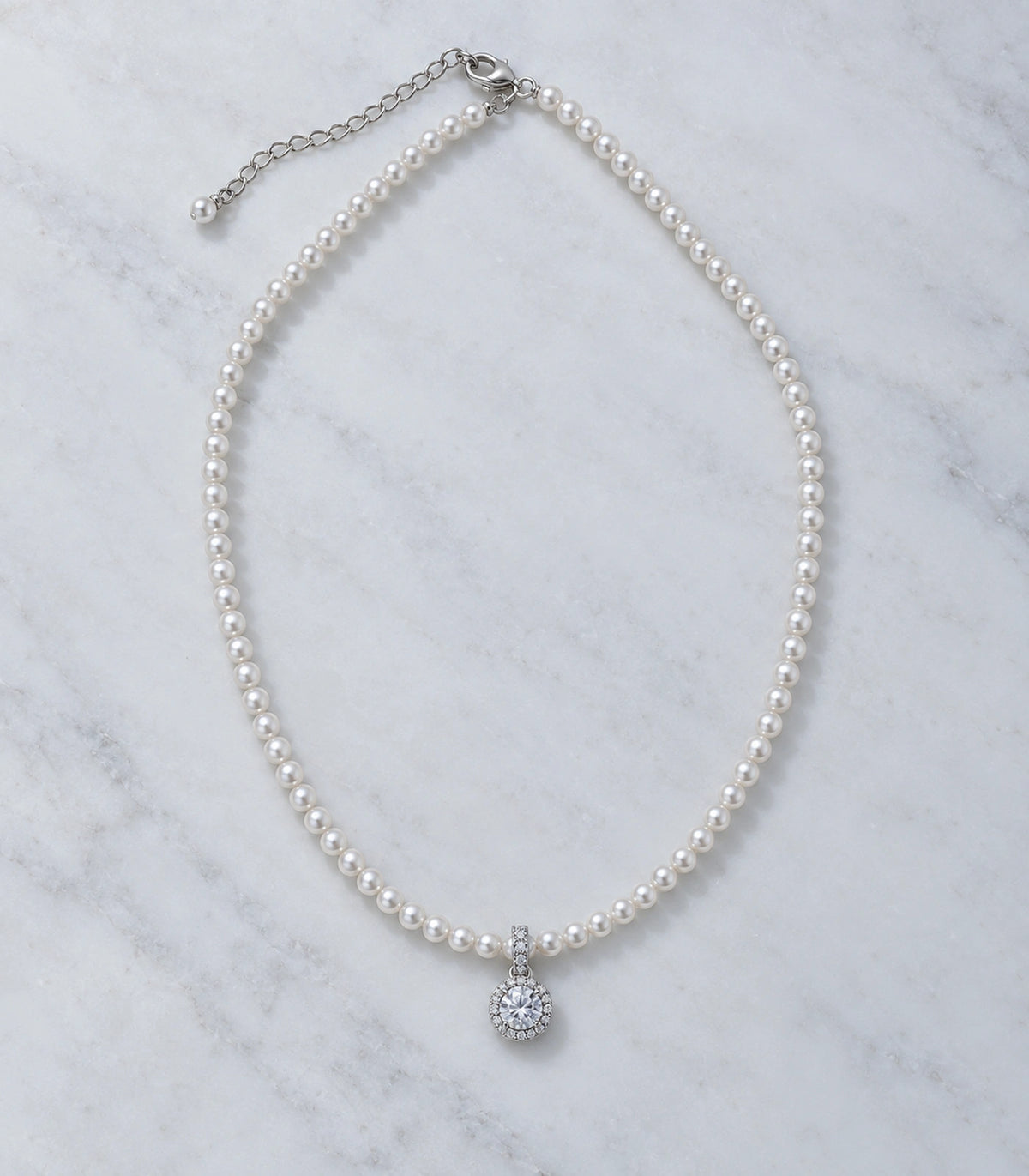 JIMIKI Silver-Tone Halo Crystal Pearl Necklace in Silver-tone / clear / white, arranged in an editorial flat lay
