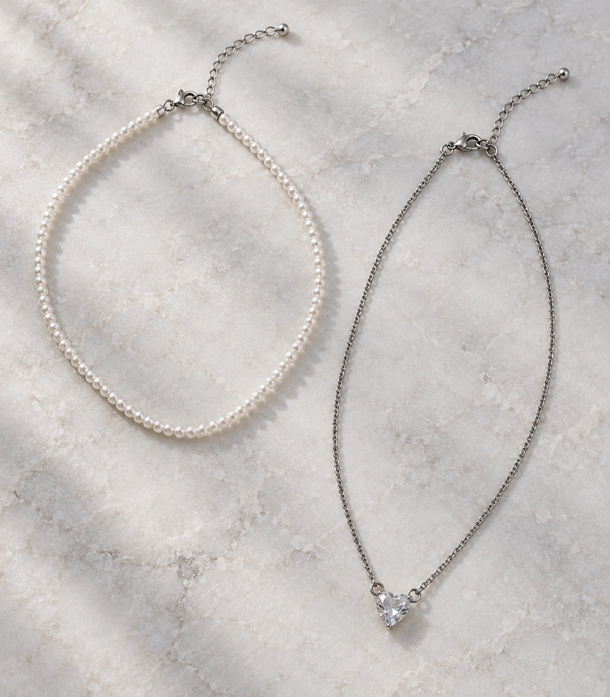 JIMIKI Silver-Tone Heart Layered Pearl Necklace Set in Silver-tone / clear / white, arranged in an editorial flat lay
