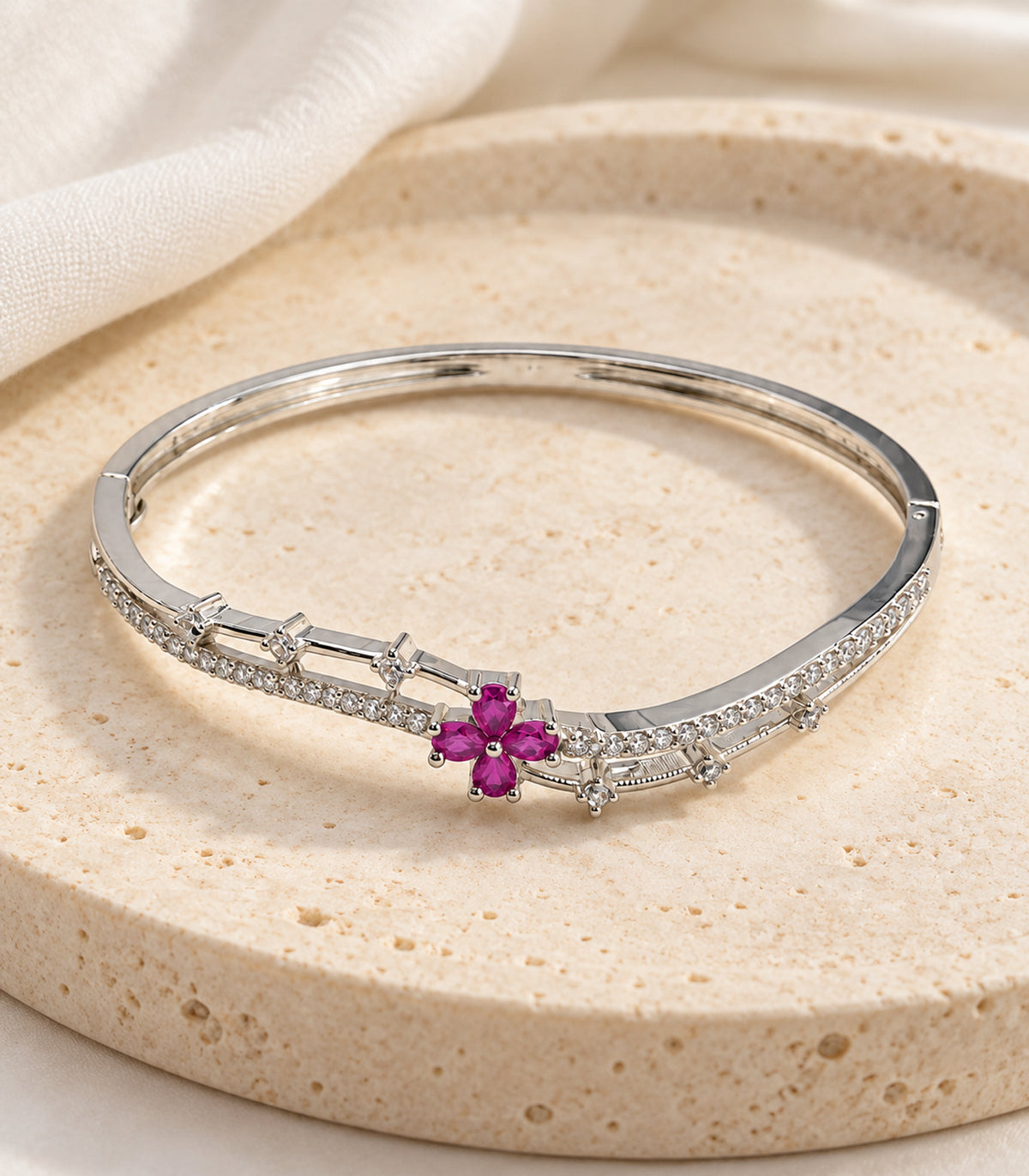 Silver-tone magenta flower and clear bar bangle — editorial flatlay view; one bangle