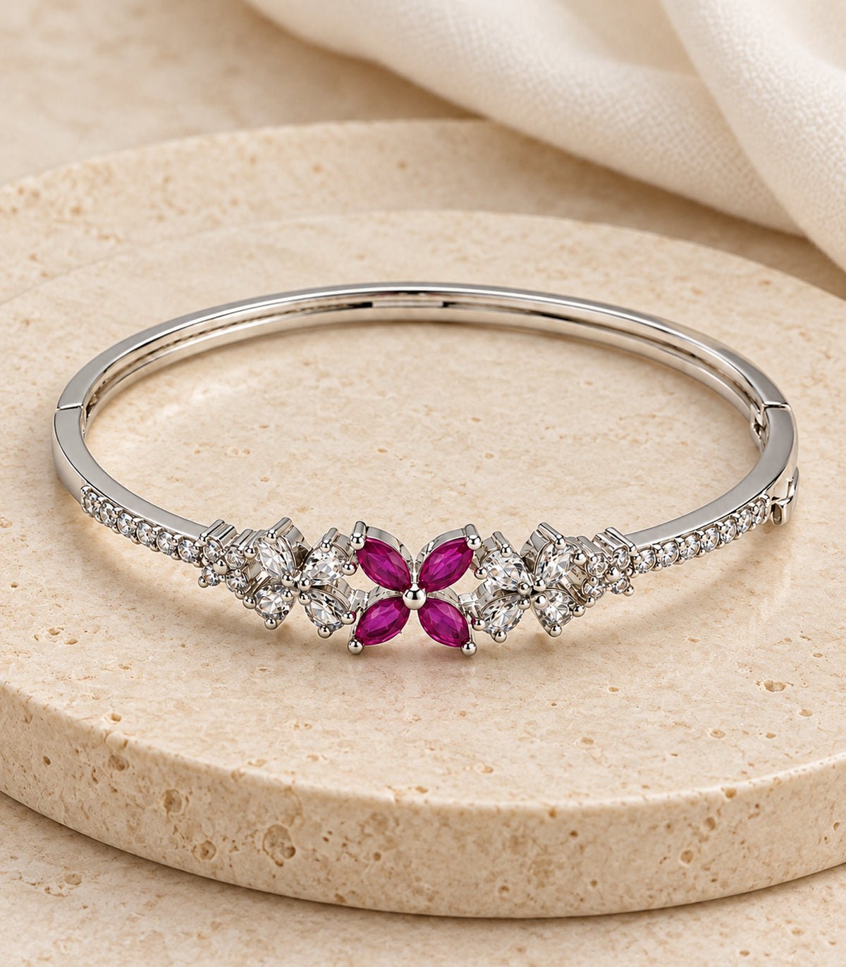 Single complete silver-tone magenta and clear flower bangle in an editorial flatlay