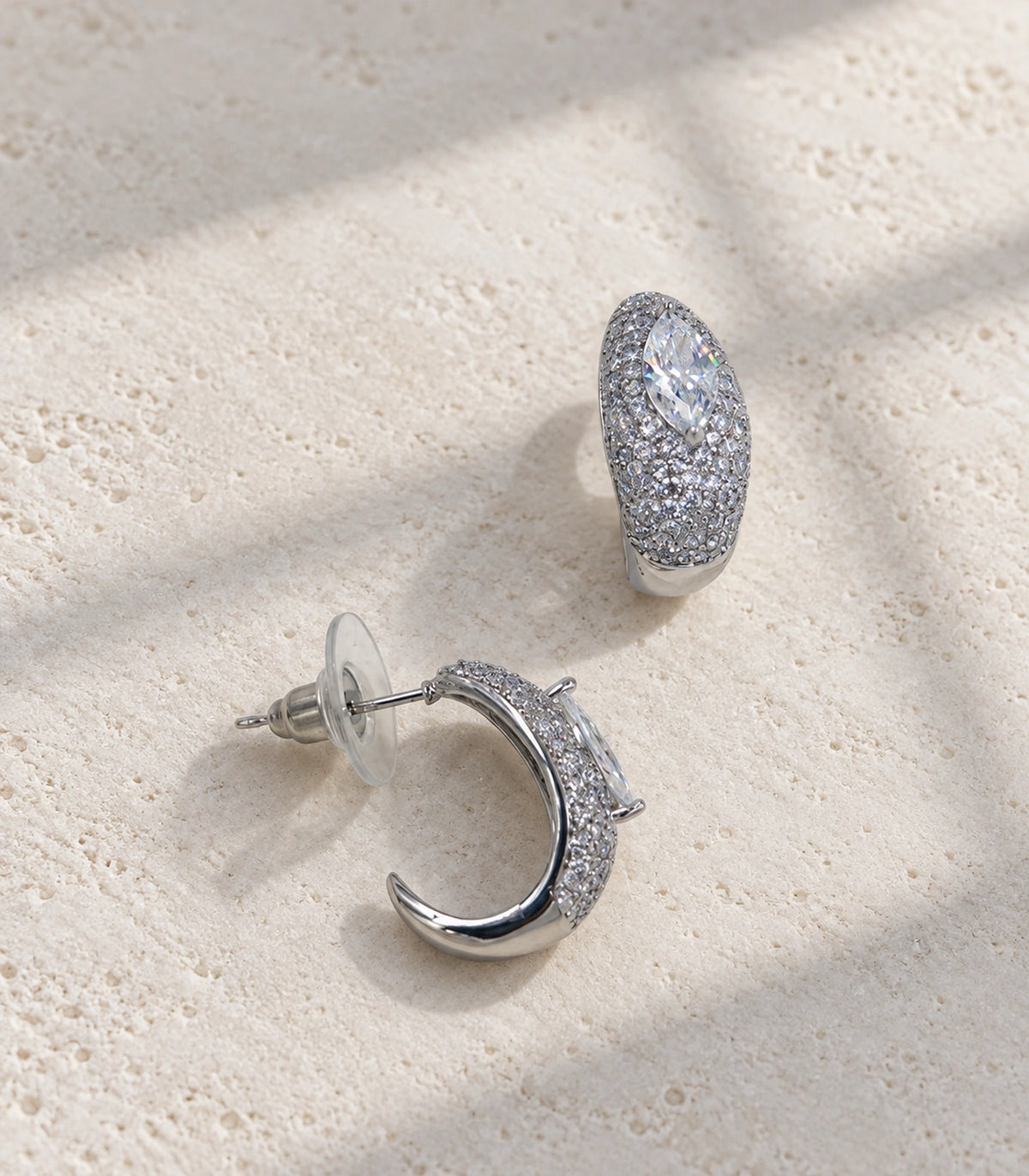 JIMIKI marquise pave open hoop earring pair in silver tone in an editorial flat lay #color_silver tone