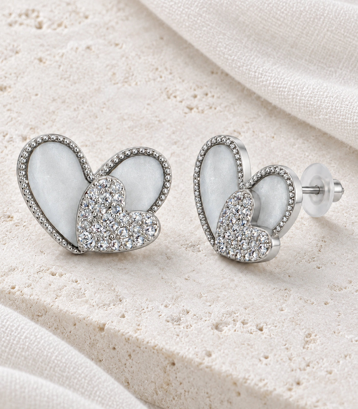 JIMIKI Open Heart Pave Heart Stud Earring Pair in Silver tone, editorial flat lay #color_silver tone