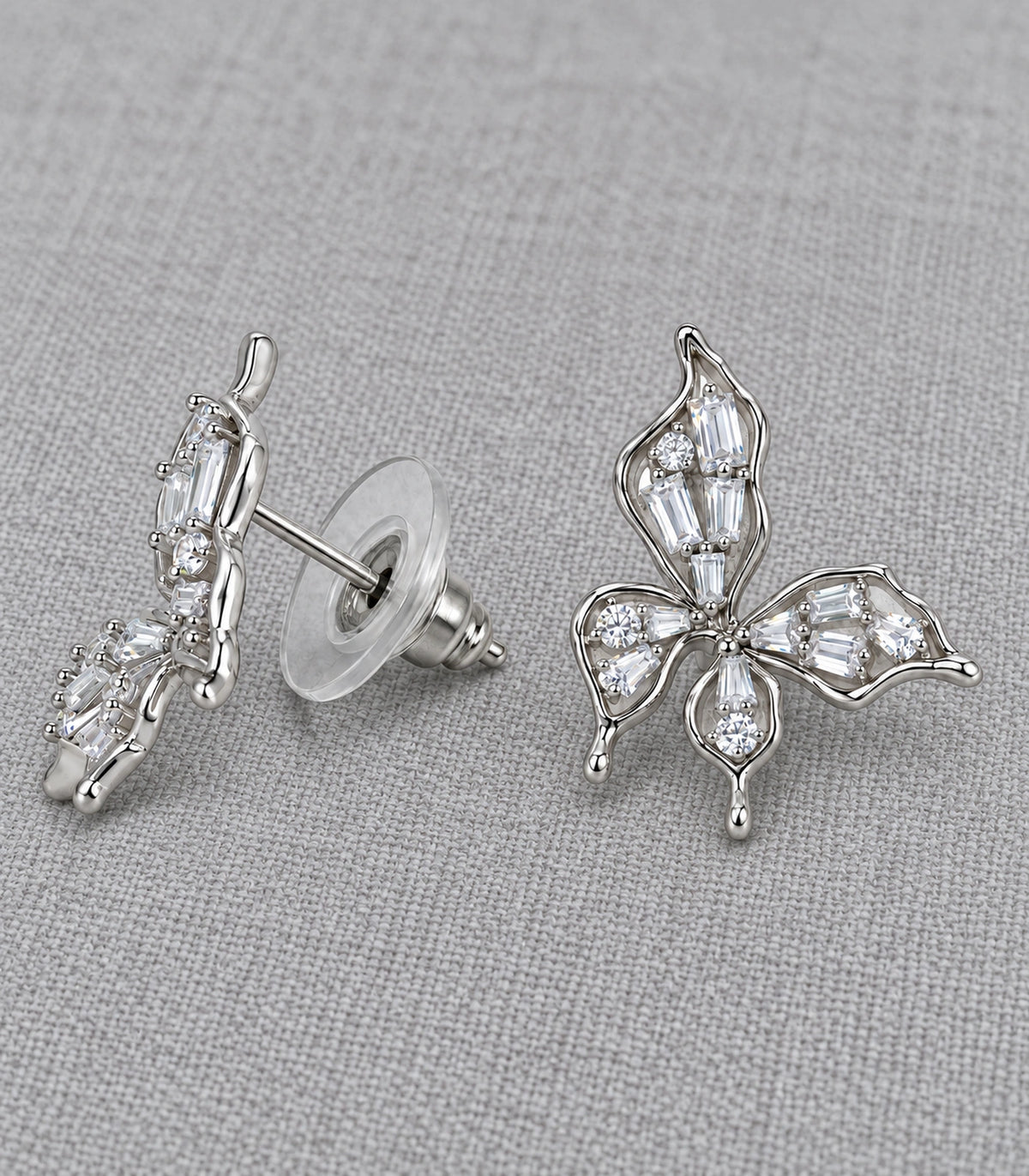 JIMIKI Openwork Baguette Crystal Butterfly Stud Earring Pair in Silver-tone, editorial flat lay #color_silver-tone