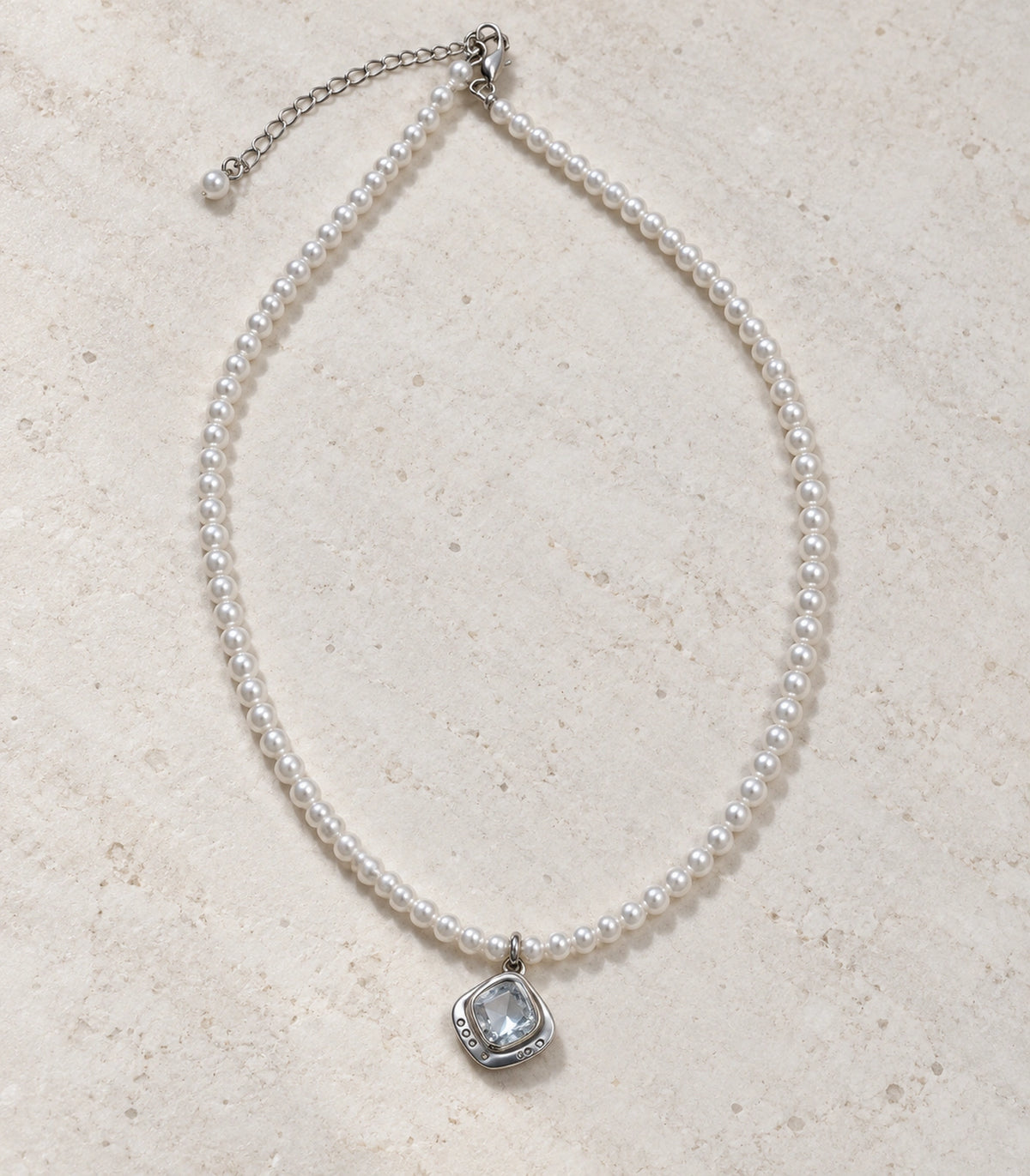 JIMIKI Silver-Tone Organic Cushion Crystal Pearl Necklace in Silver-tone / clear / white, arranged in an editorial flat lay