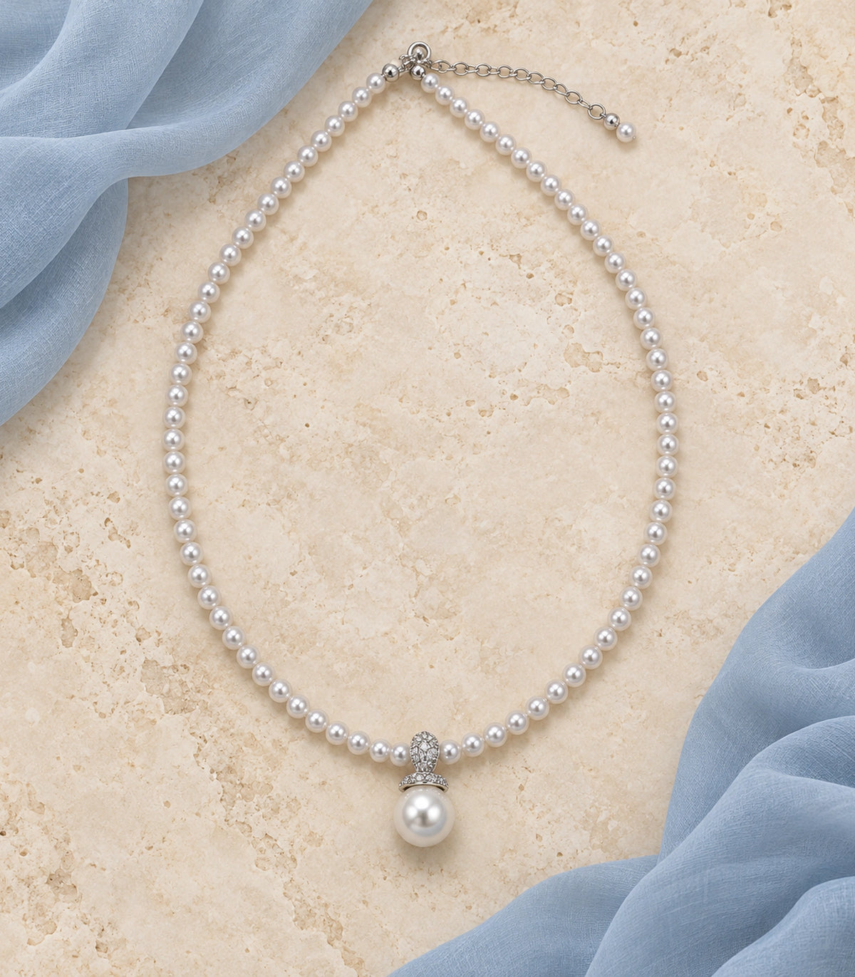 JIMIKI Silver-Tone Pavé Bail Pearl Drop Necklace in Silver-tone / white, arranged in an editorial flat lay