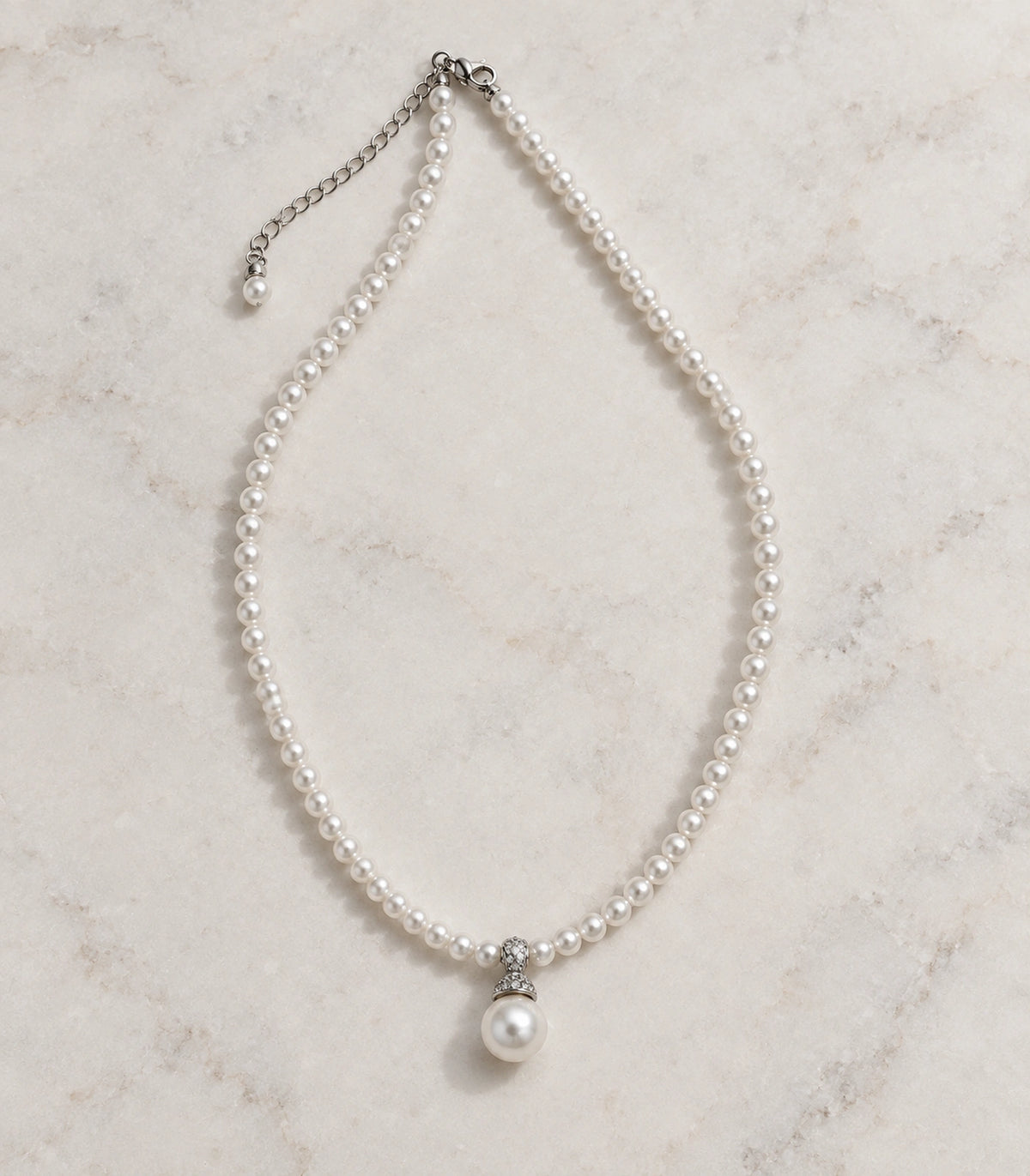 JIMIKI Silver-Tone Pavé Cap Pearl Drop Necklace in Silver-tone / clear / white, arranged in an editorial flat lay
