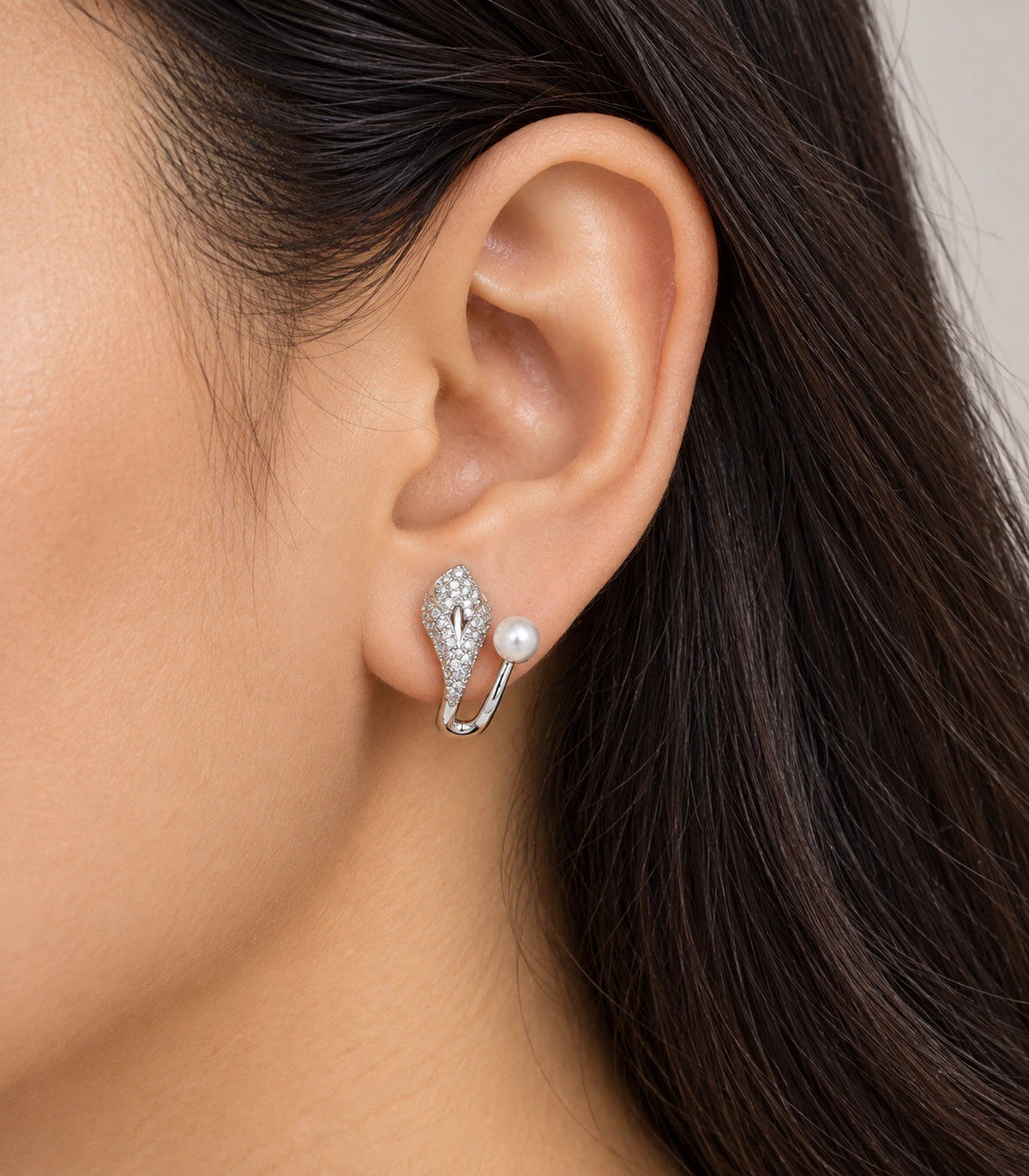 Silver-tone leaf and white pearl-style ear jacket earring worn on the ear
