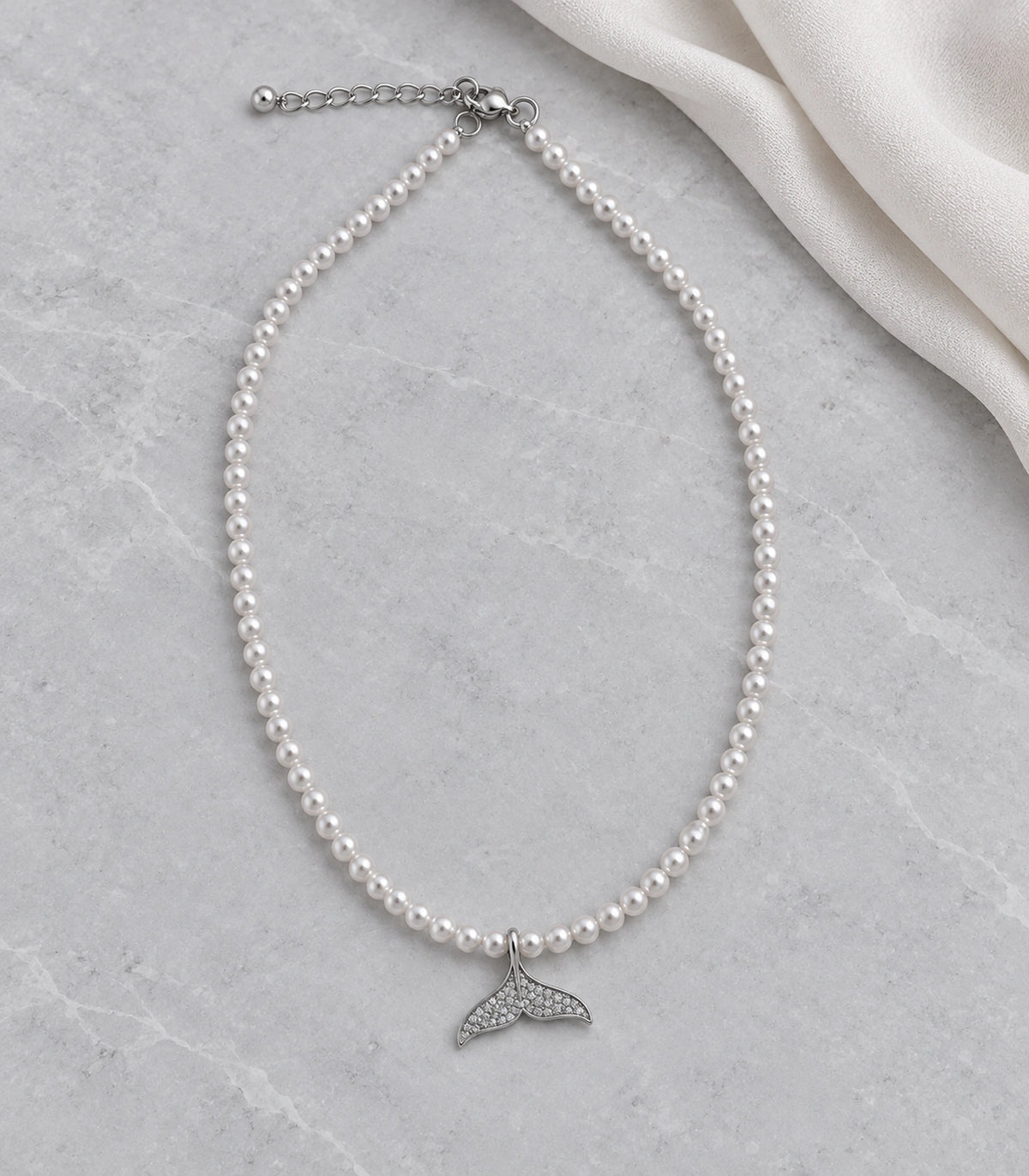 JIMIKI Pavé Whale Tail Pearl Necklace in Silver-tone, arranged in an editorial flat lay #color_silver-tone
