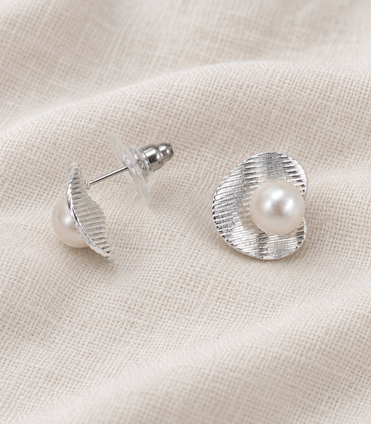 JIMIKI Ribbed Curved Disc Pearl Stud Earring Pair in Silver tone / White, editorial flat lay #color_silver tone / white