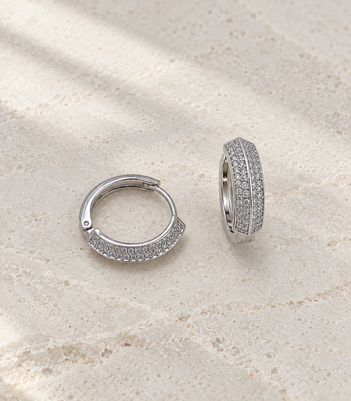 JIMIKI ridged pave hinged hoop earring pair in silver tone, editorial flat lay #color_silver tone