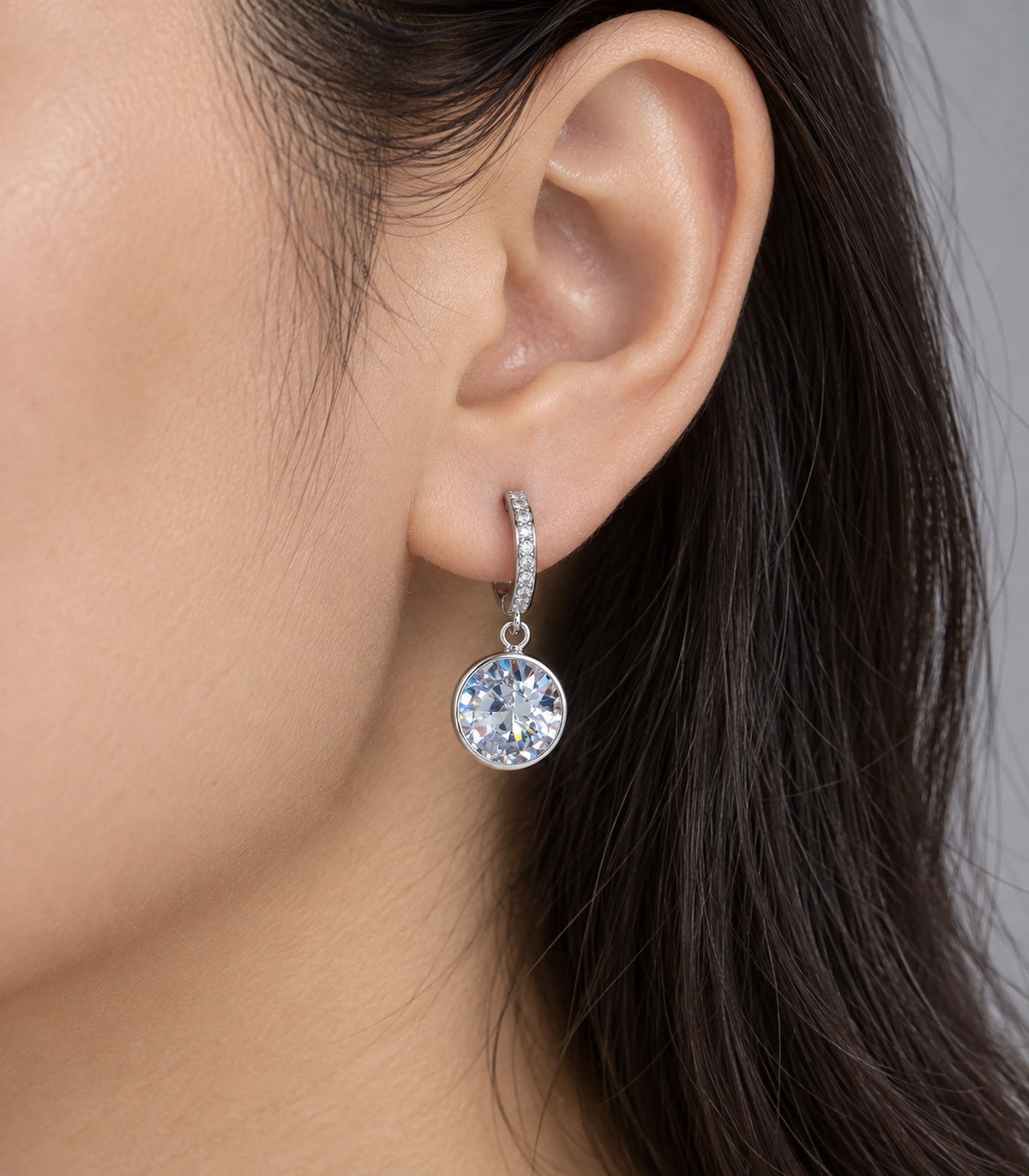 JIMIKI Silver-Tone Round Solitaire Drop Huggie Earrings in Silver / Clear, close-up detail