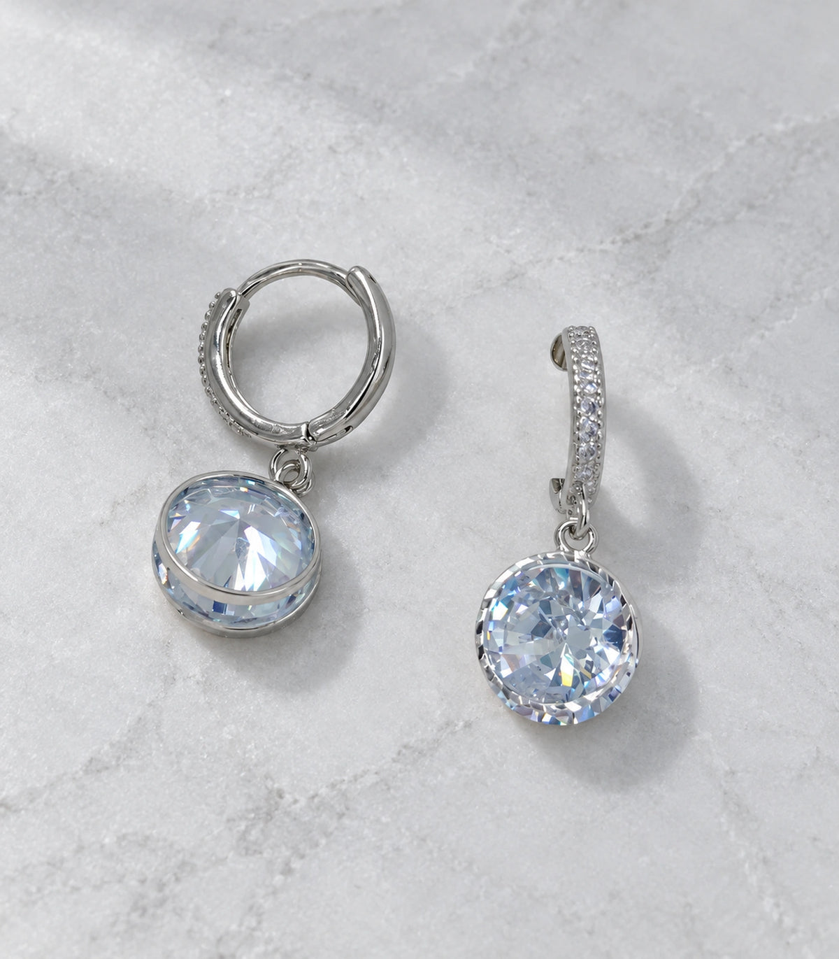 JIMIKI Silver-Tone Round Solitaire Drop Huggie Earrings in Silver / Clear, editorial flat lay