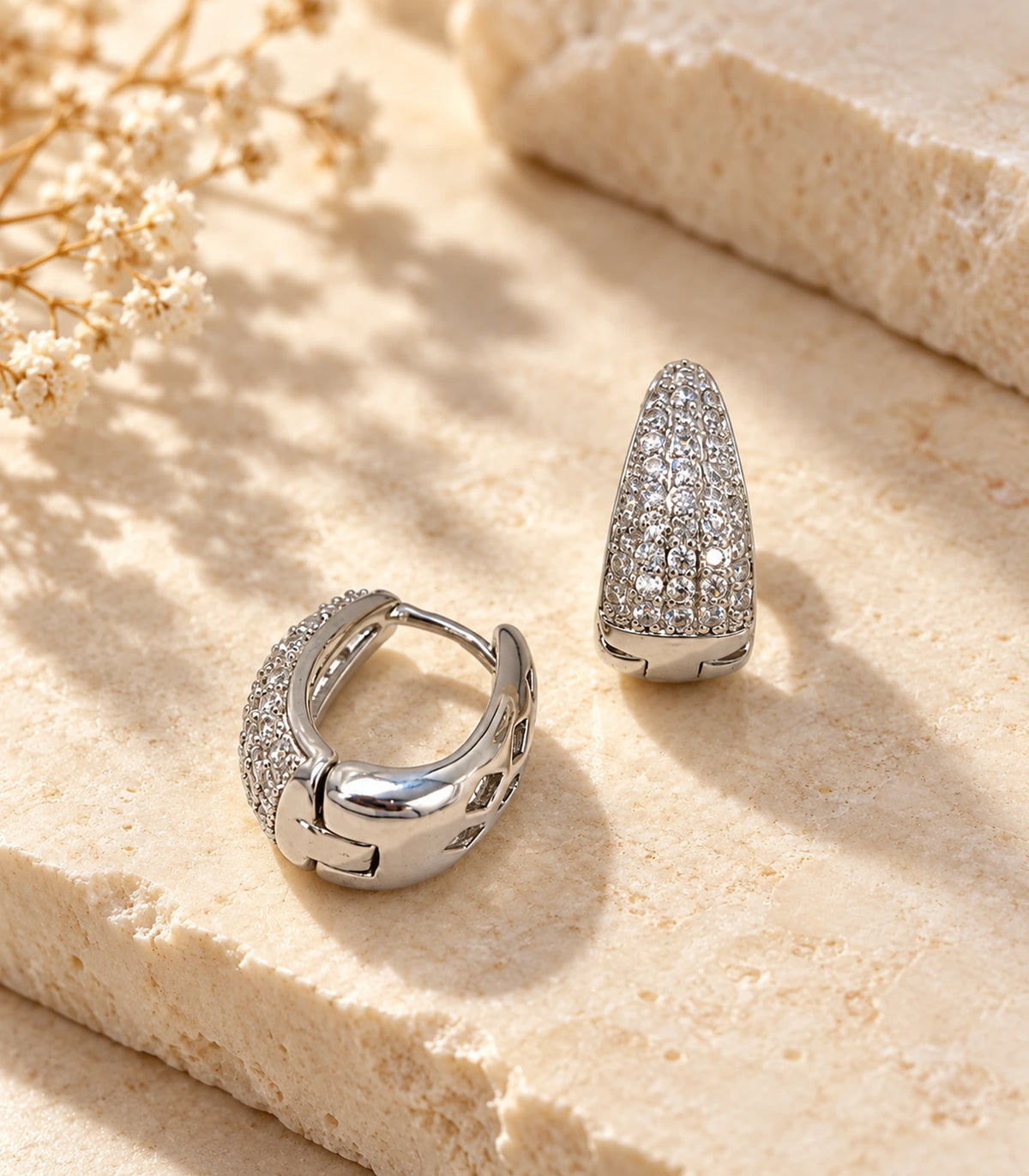 JIMIKI Silver tapered pave huggie hoop earrings, pair styled on textured stone #color_silver