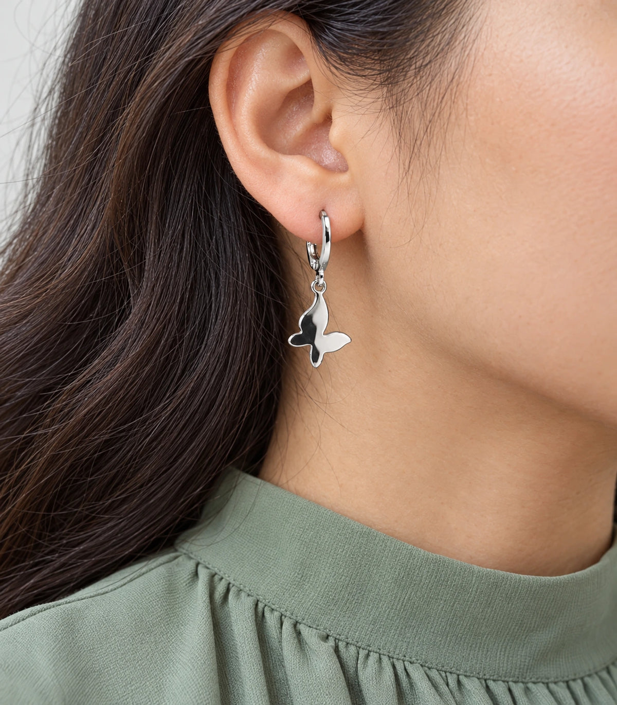 Closeup of a silver-tone smooth butterfly hoop earring from the three-pair set