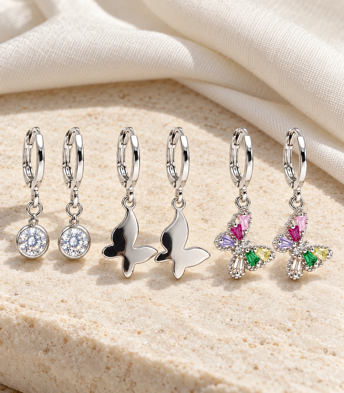 Complete six-earring silver-tone crystal and butterfly set styled on stone and linen