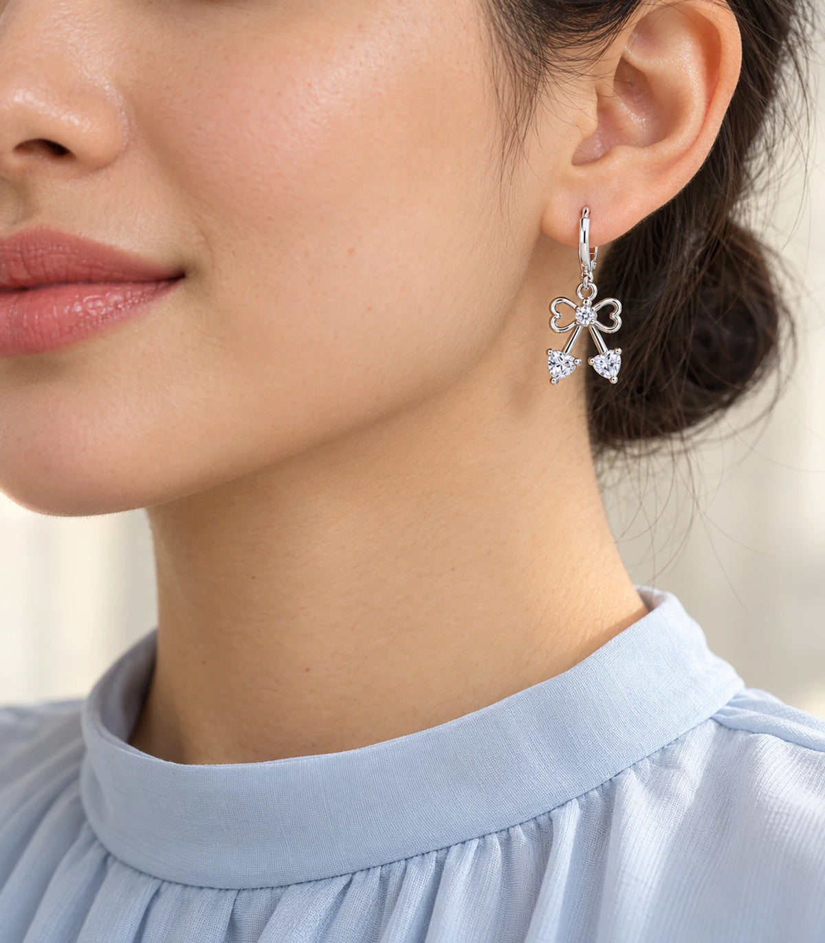 Silver-tone hoop earring from the three-pair set worn with blue high-neck clothing
