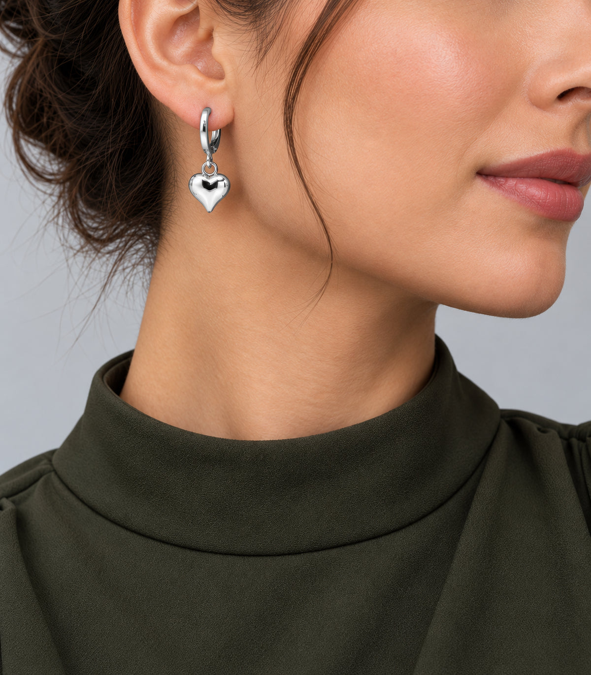 One polished silver-tone heart charm hoop worn on the earlobe; design included in the three-pair set