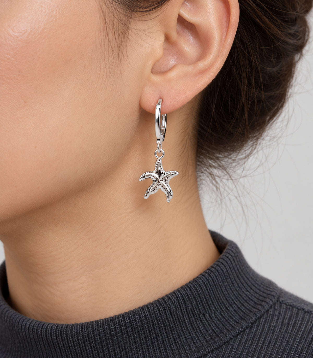 One textured five-arm starfish hoop from the three-pair silver-tone set, worn on one ear.