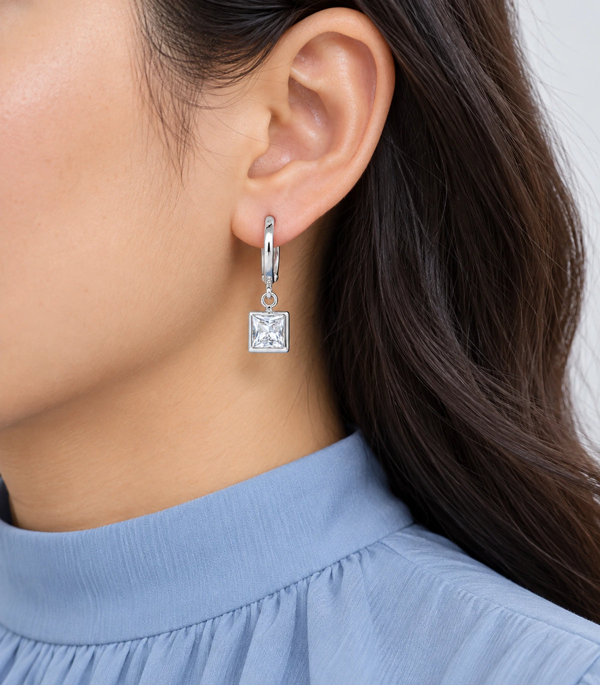 Worn square clear bezel-crystal hoop from the three-pair silver-tone set